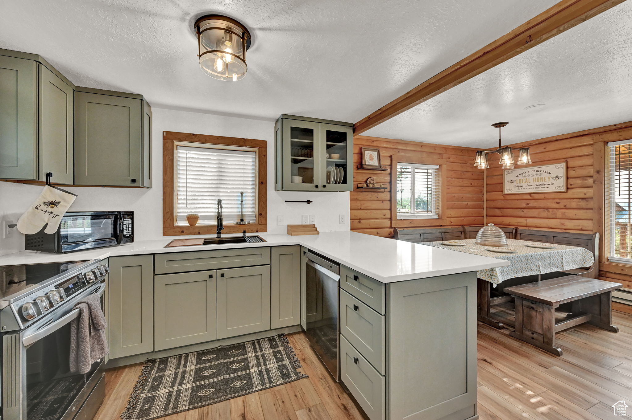 Kitchen featuring wood walls, kitchen peninsula, stainless steel appliances, and rustic walls