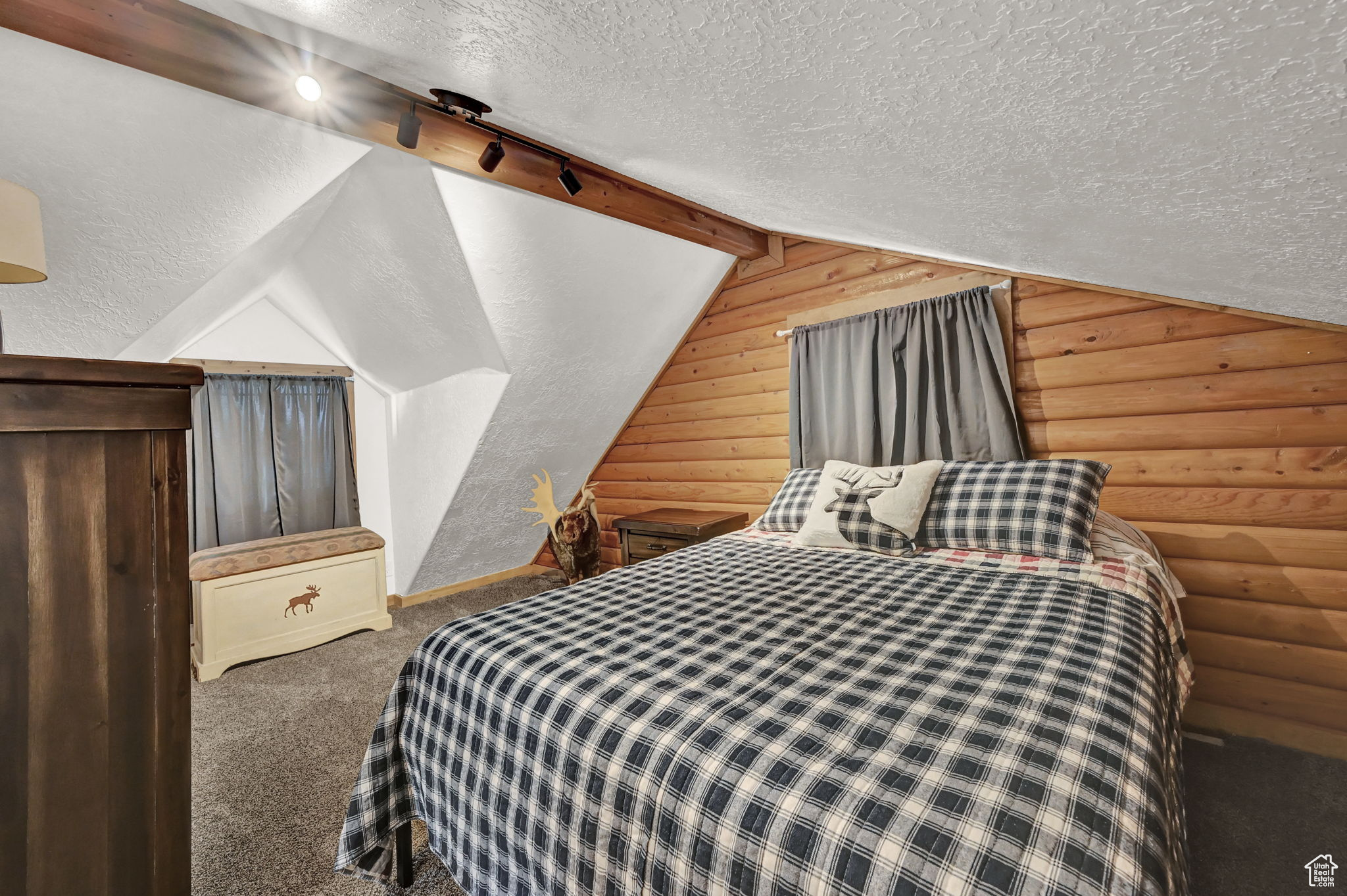 Bedroom featuring vaulted ceiling with beams, log walls, and a textured ceiling