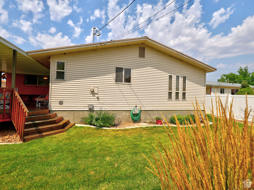 View of home's exterior featuring a deck and a yard