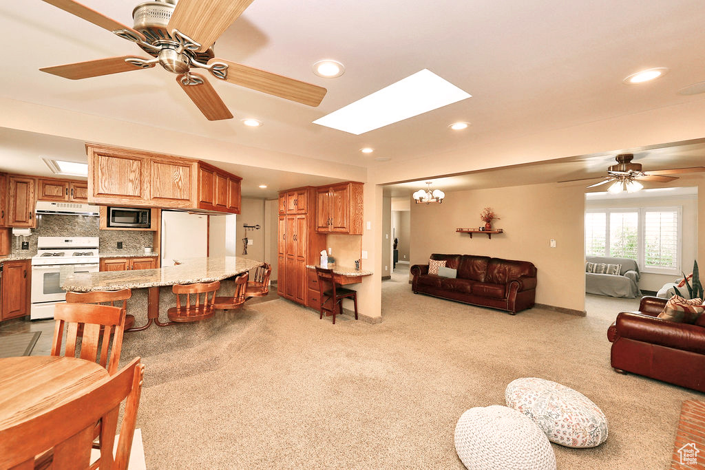 Living room with a skylight, light carpet, and ceiling fan