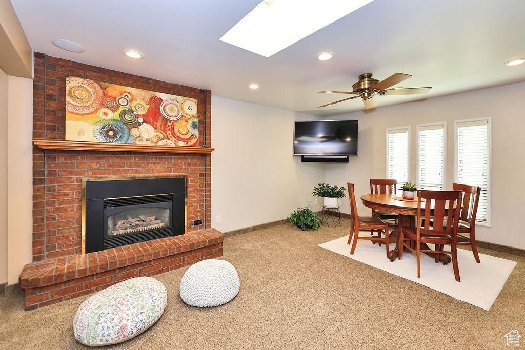 Dining room with a skylight, a brick fireplace,  and ceiling fan