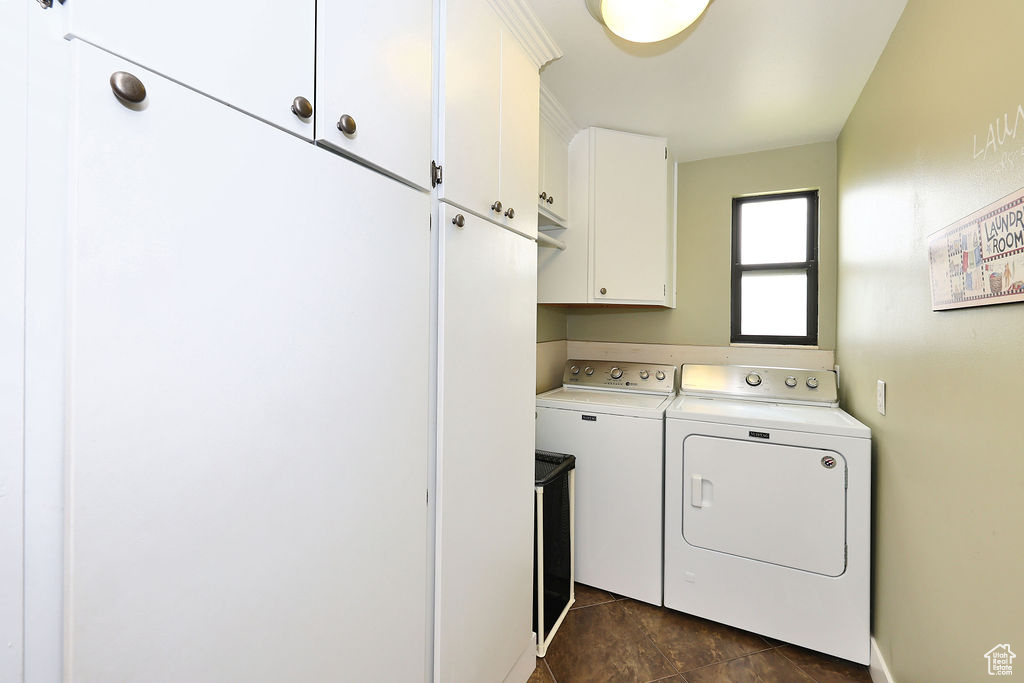 Washroom featuring dark tile patterned floors, separate washer and dryer, and cabinets