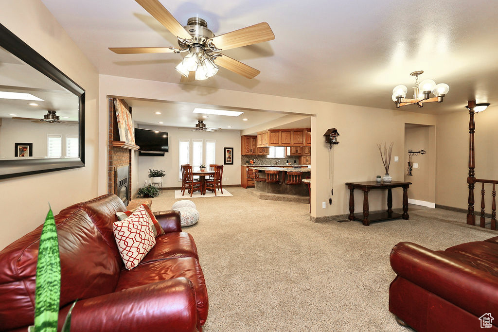 Carpeted living room with ceiling fan mid century chandelier and a brick fireplace