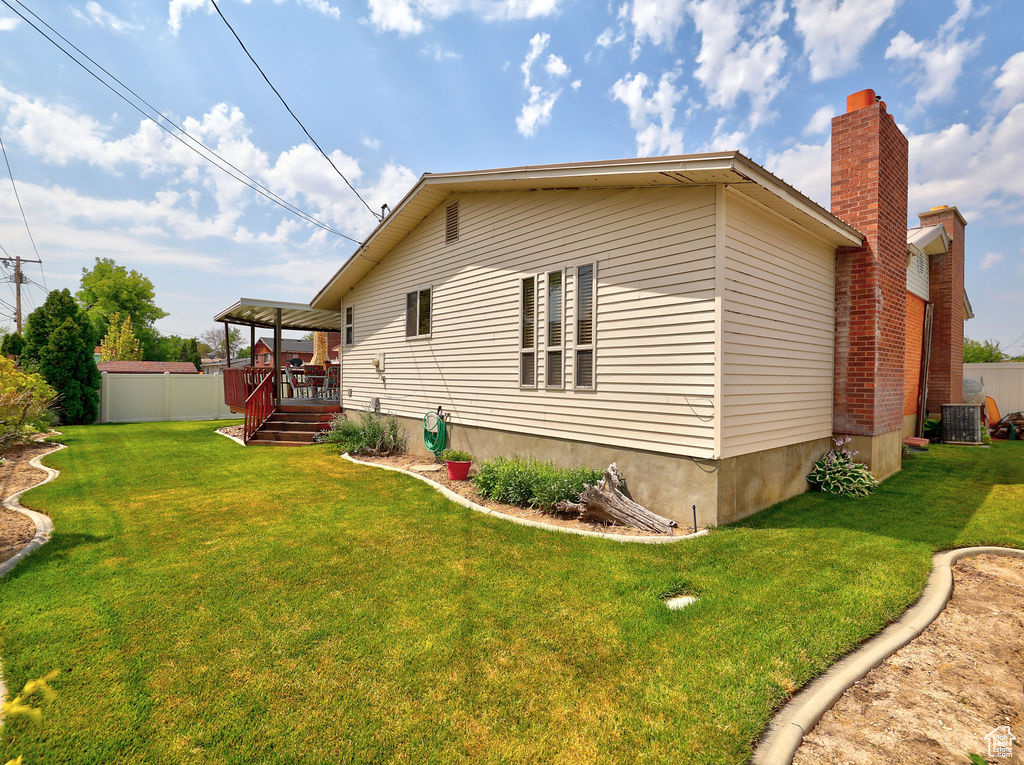 View of side of property with  a deck, and a lawn