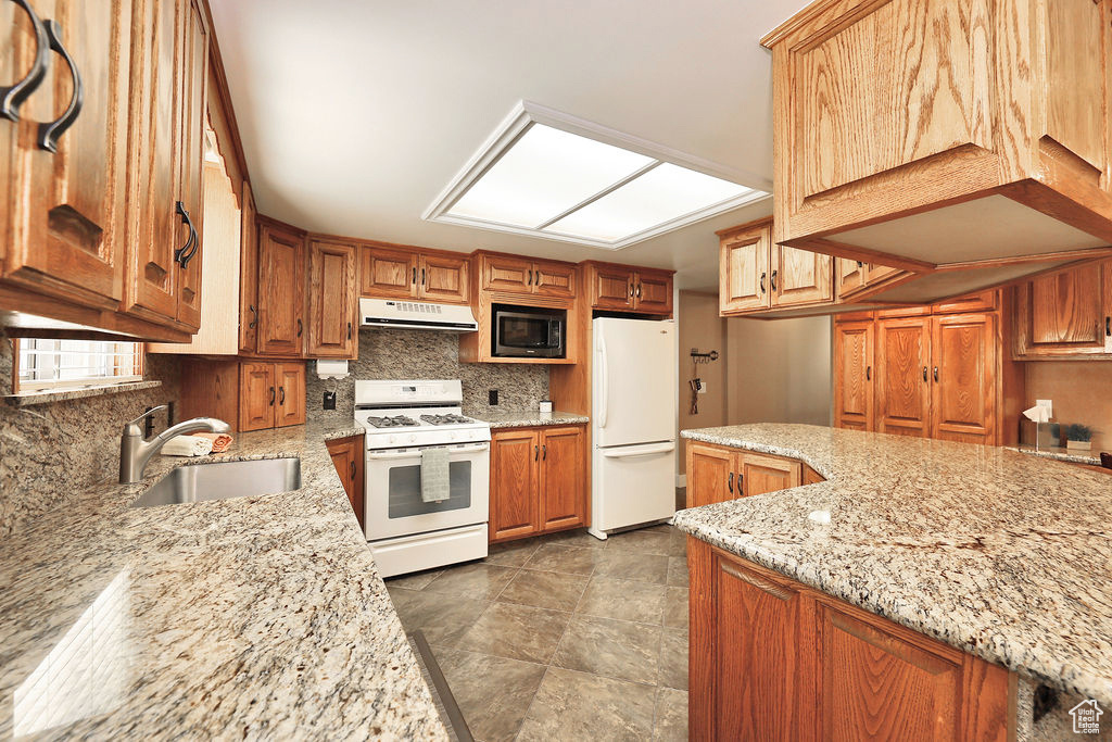 Kitchen with tasteful backsplash, light stone counters