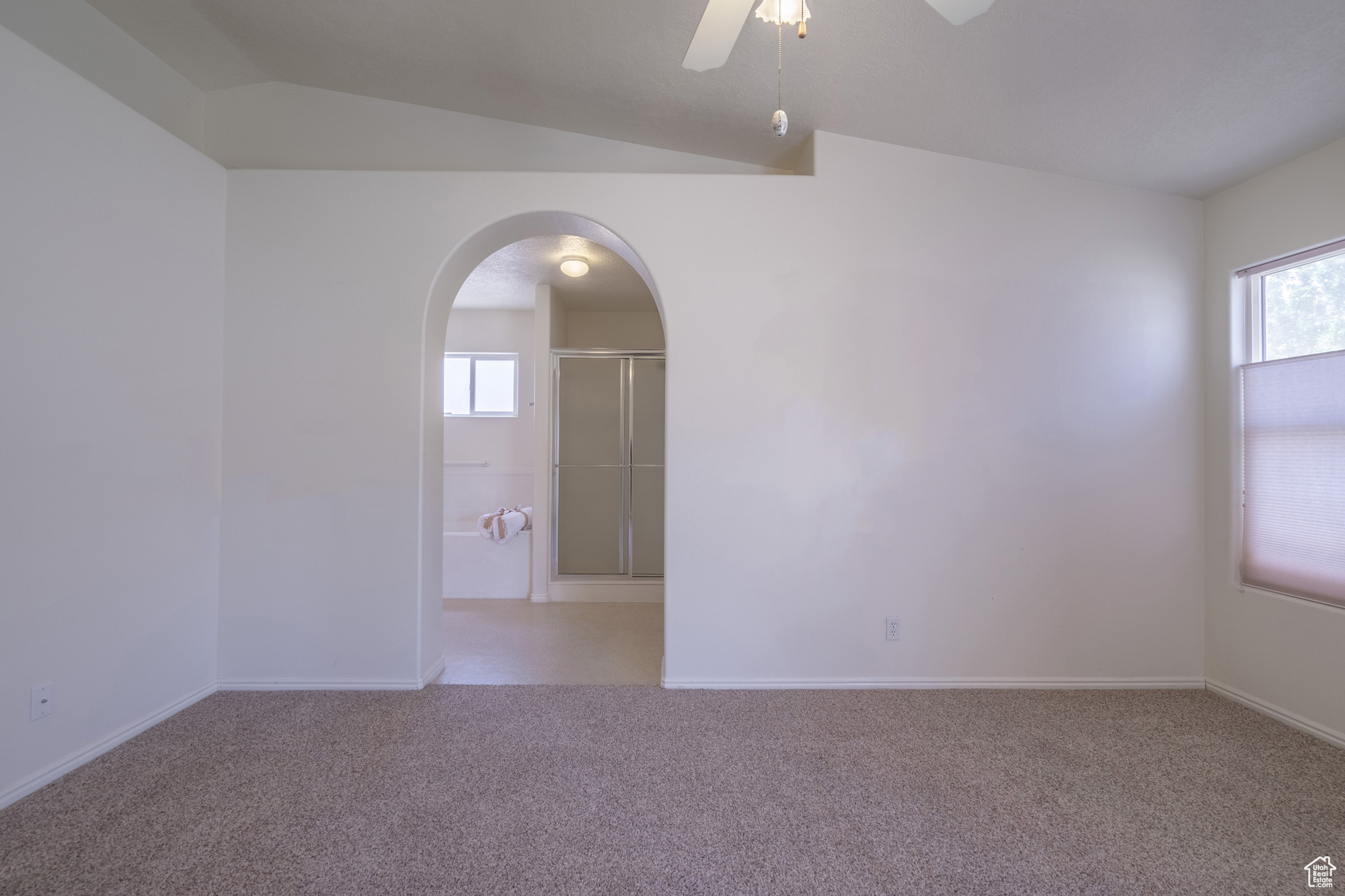 Primary bedroom with ceiling fan and lofted ceiling