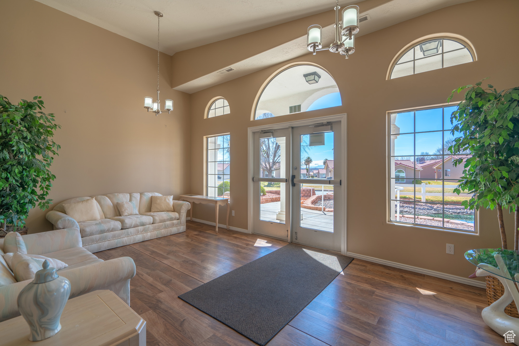 Living room featuring a high ceiling, french doors, dark hardwood / wood-style flooring, and a notable chandelier