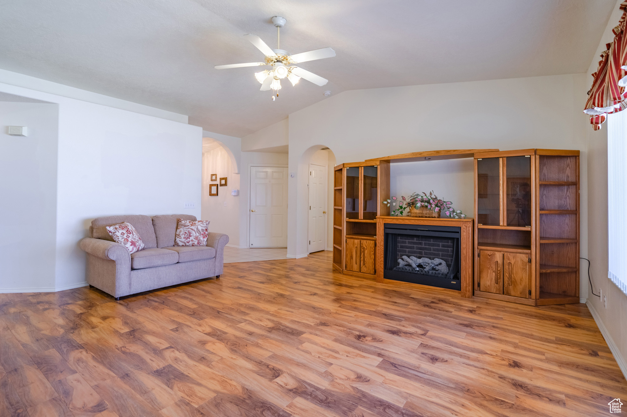 Living room with ceiling fan, wood-type flooring, and vaulted ceiling