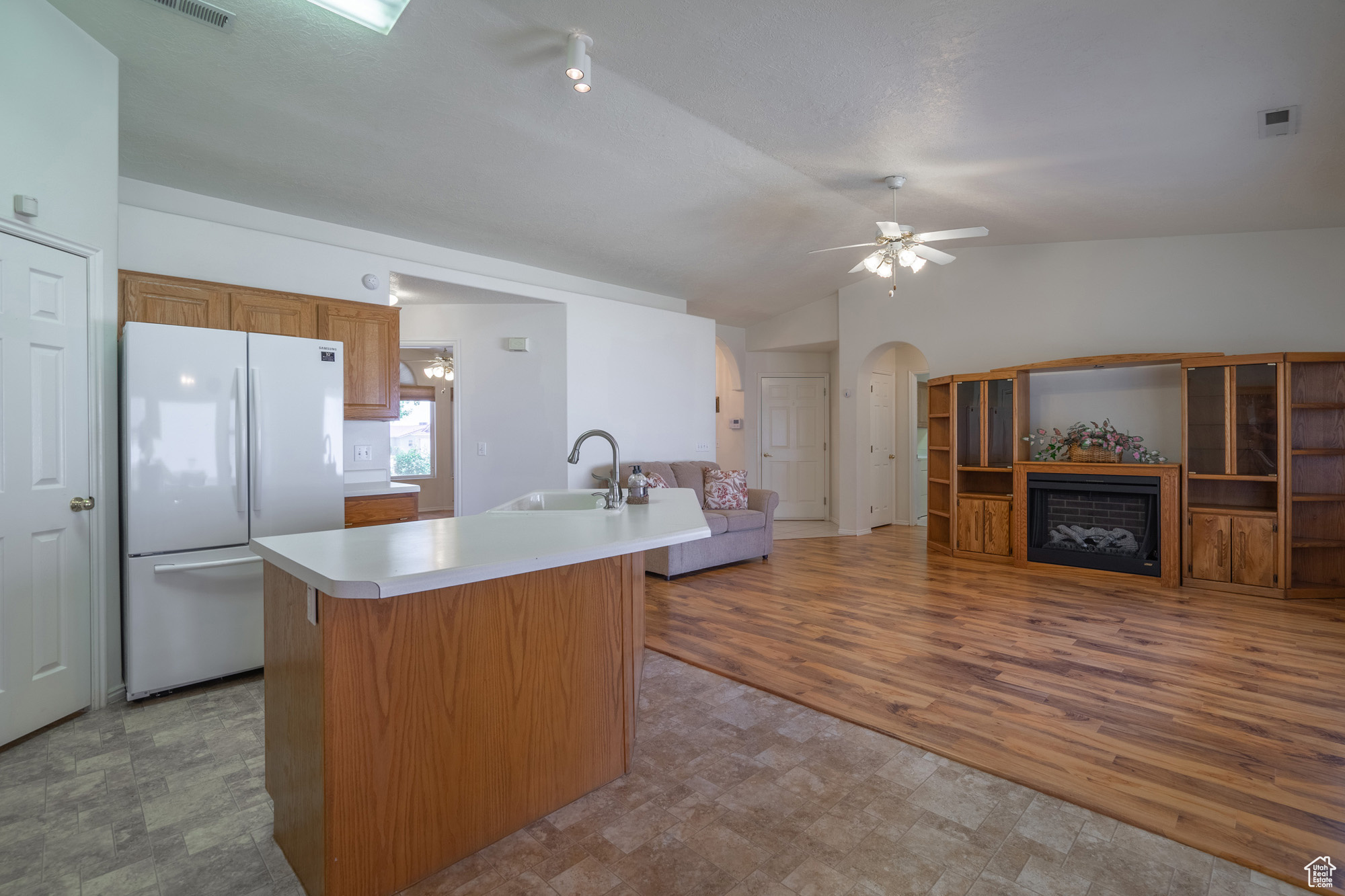 Kitchen featuring white refrigerator, ceiling fan, hardwood / wood-style floors, sink, and lofted ceiling