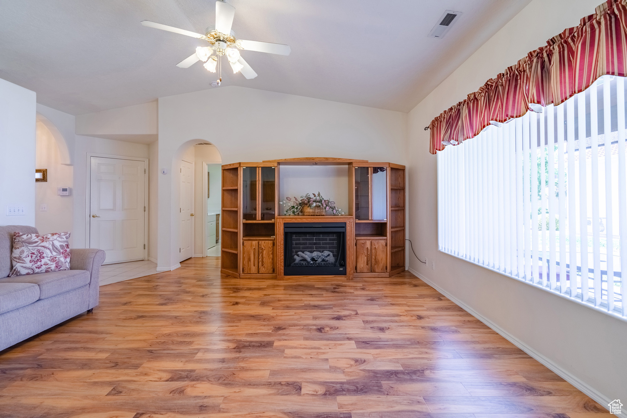 Unfurnished living room featuring lofted ceiling, wood-type flooring, and ceiling fan