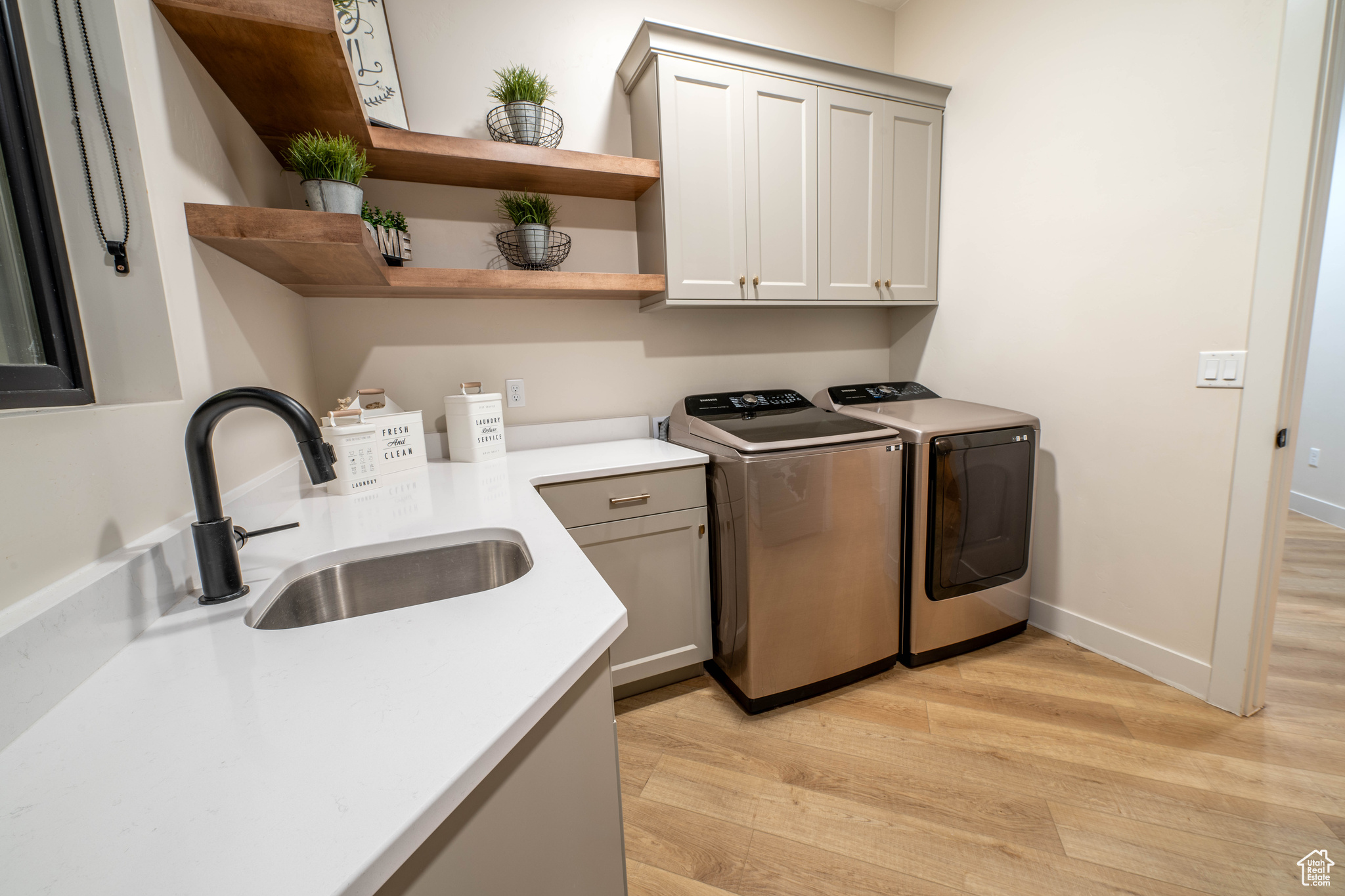 Laundry room featuring cabinets, sink, light wood-type flooring, and washing machine and clothes dryer