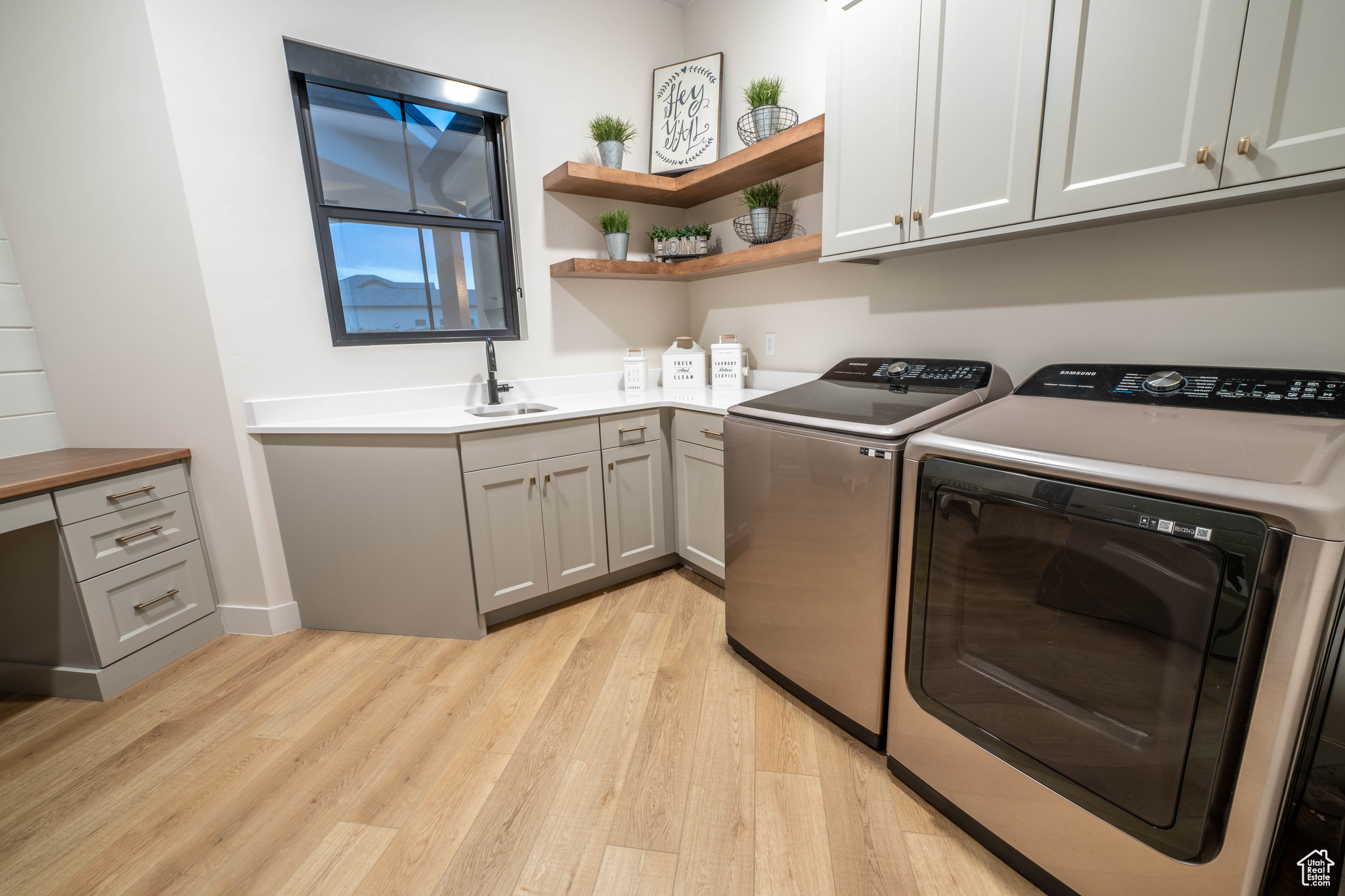 Laundry room featuring sink, light hardwood / wood-style floors, washer and clothes dryer, and cabinets