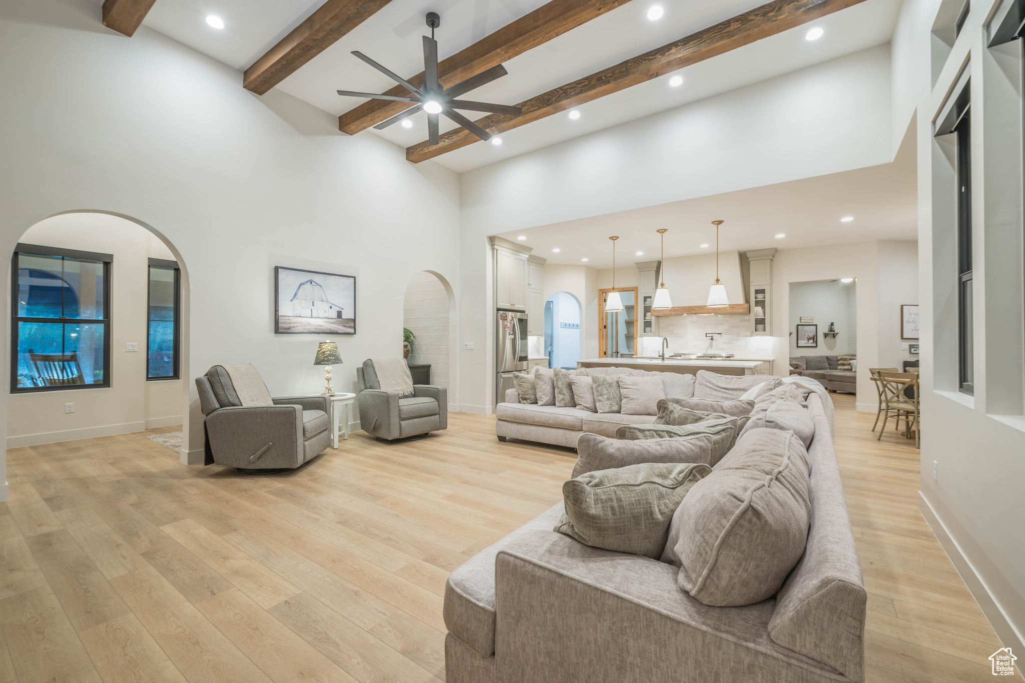 Living room with light hardwood / wood-style floors, sink, ceiling fan, and a high ceiling