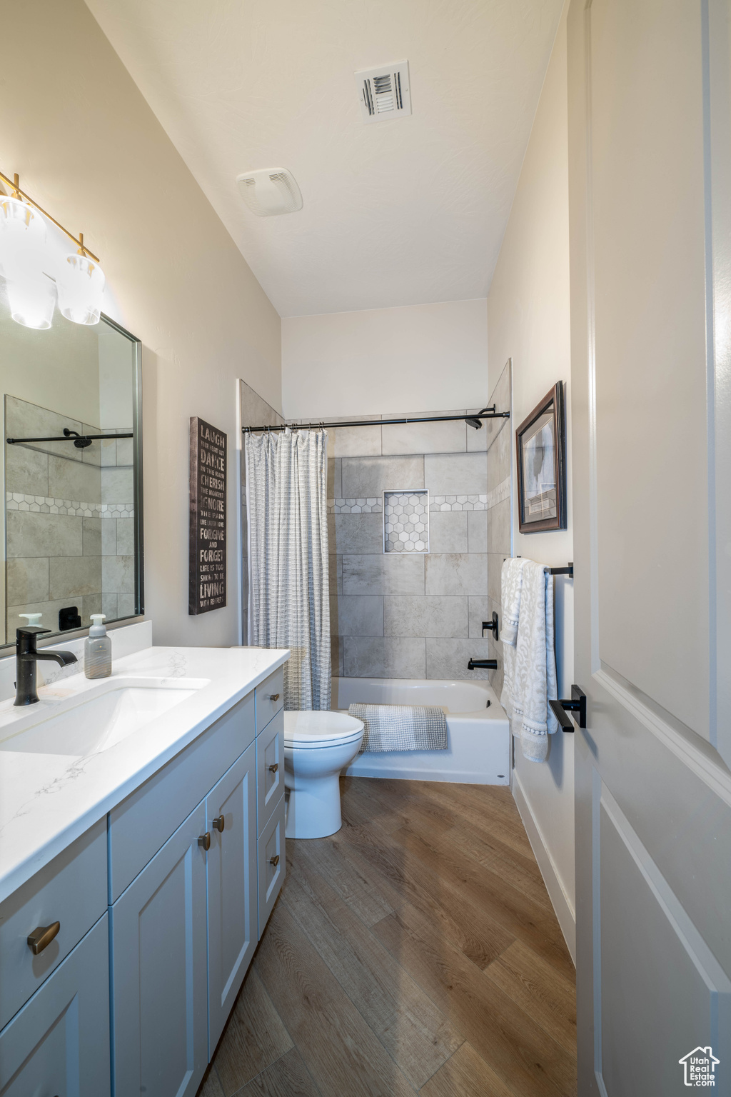 Full bathroom with shower / bath combination with curtain, hardwood / wood-style flooring, toilet, and vanity