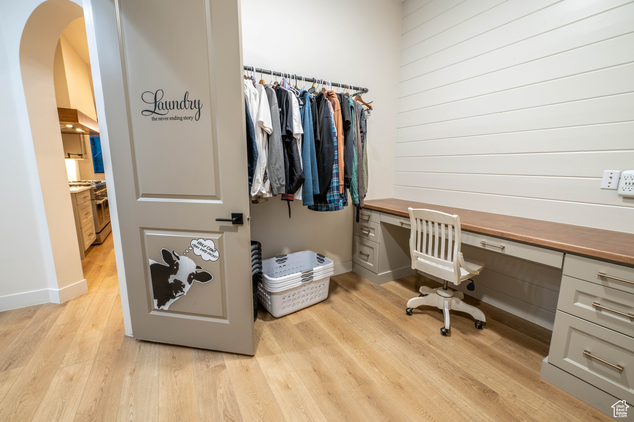 Laundry room with built in desk and light hardwood / wood-style flooring