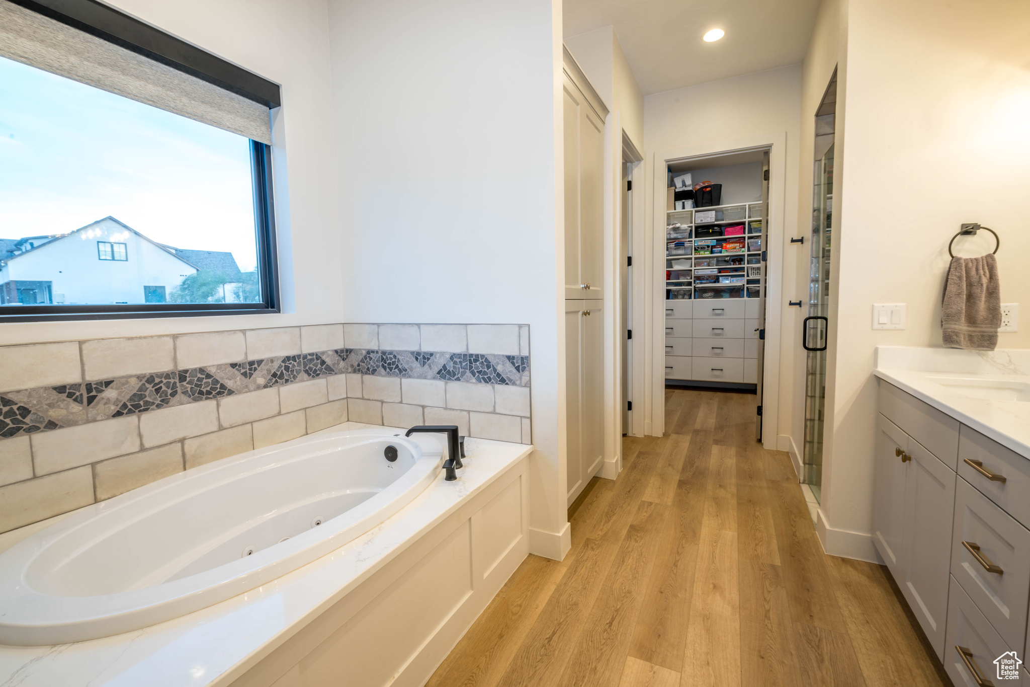 Master Bathroom featuring tiled bath, vanity, and wood-type flooring