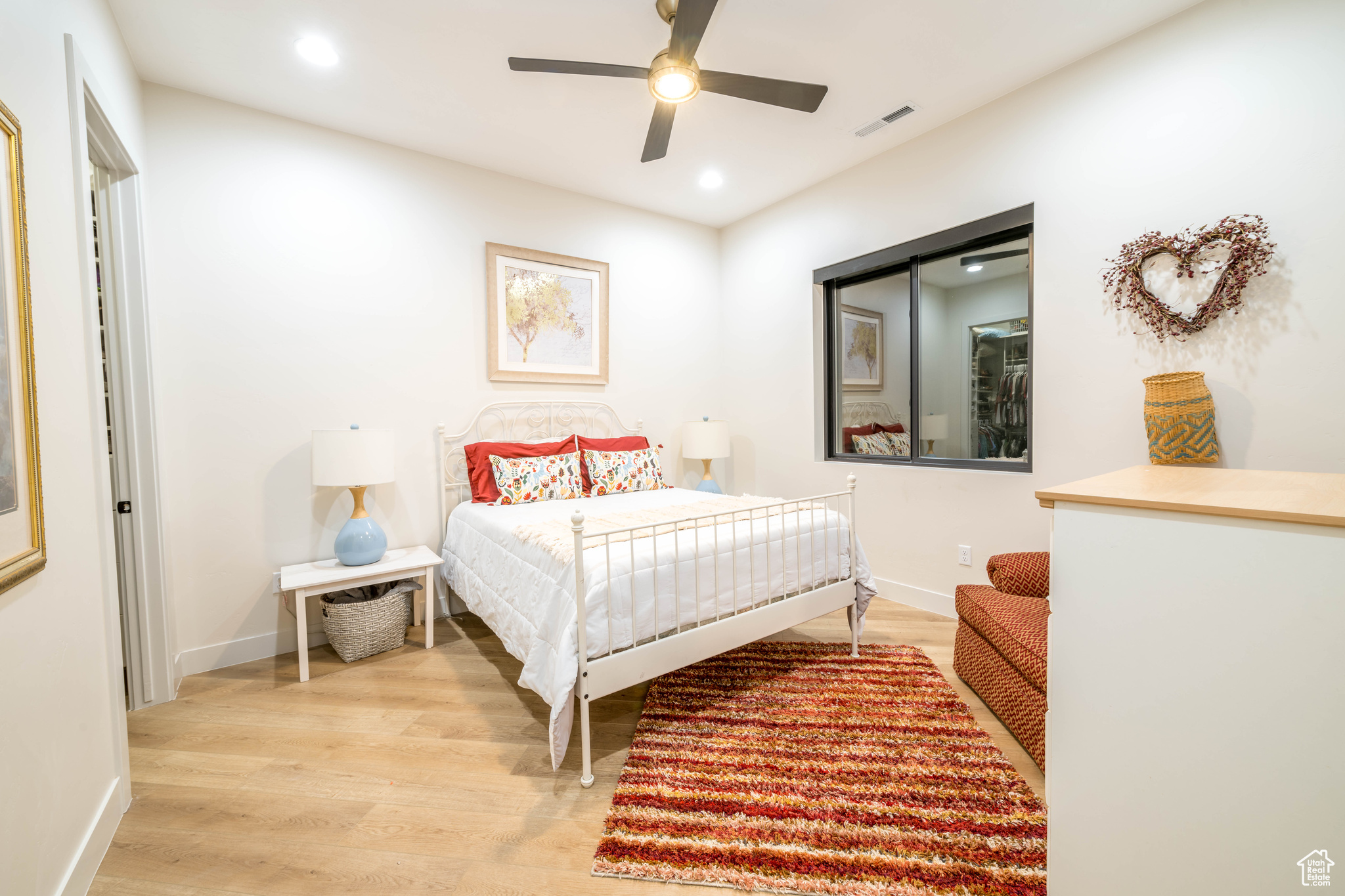 Bedroom 2 with light wood-type flooring and ceiling fan also includes walk- in closet