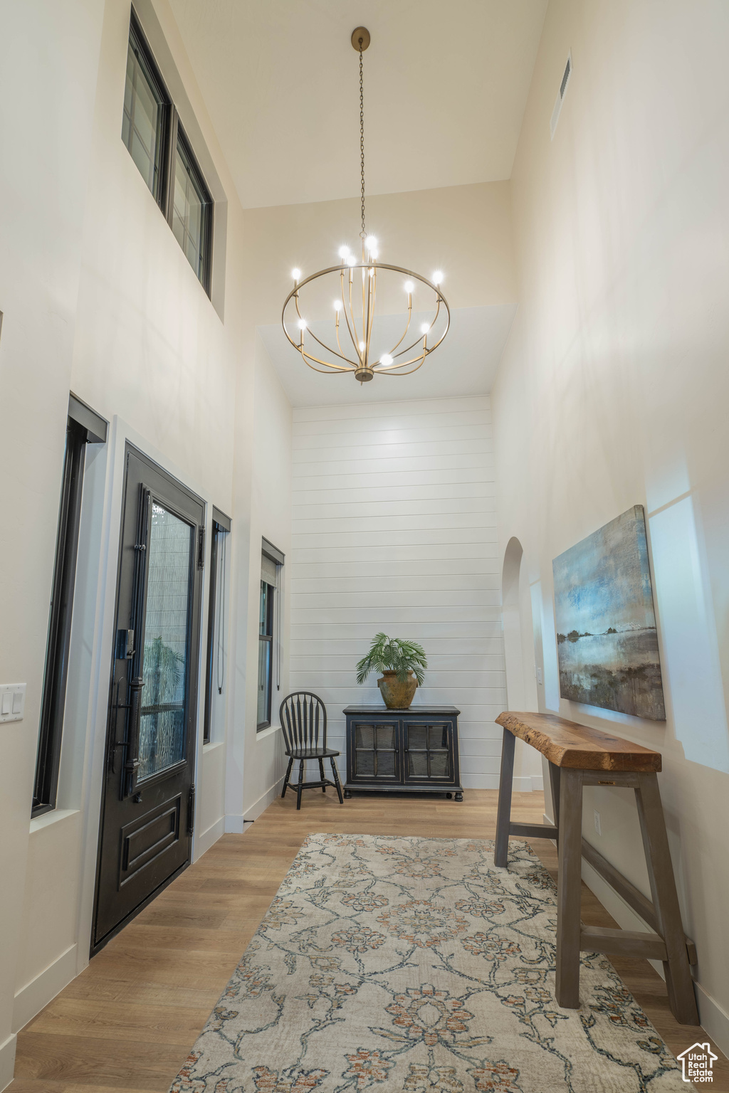 Interior space featuring a towering ceiling, wood-type flooring, and a chandelier