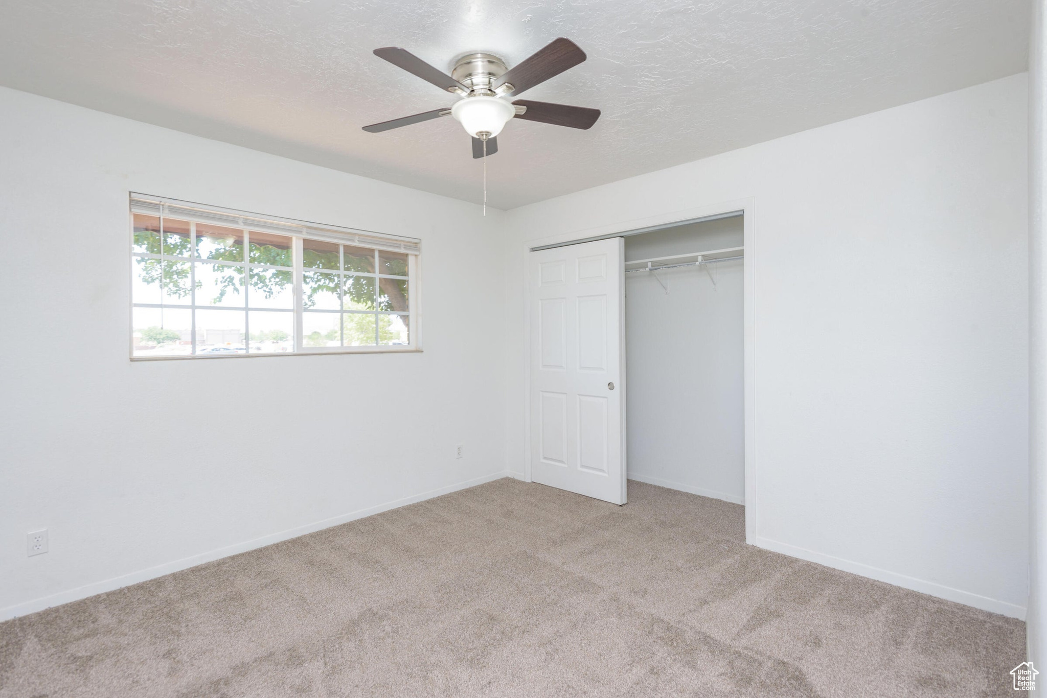 Unfurnished bedroom with a closet, ceiling fan, and light colored carpet