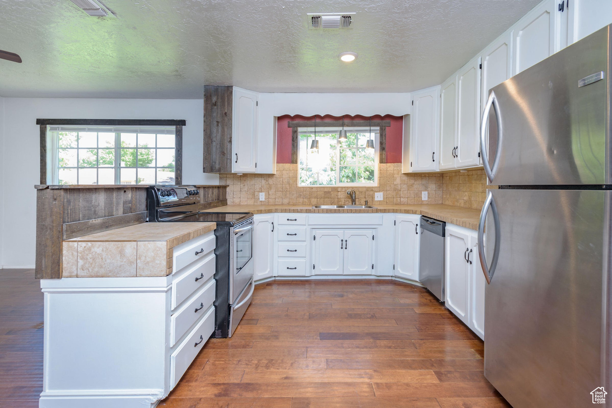 Kitchen featuring plenty of natural light, white cabinetry, dark wood-type flooring, and stainless steel appliances