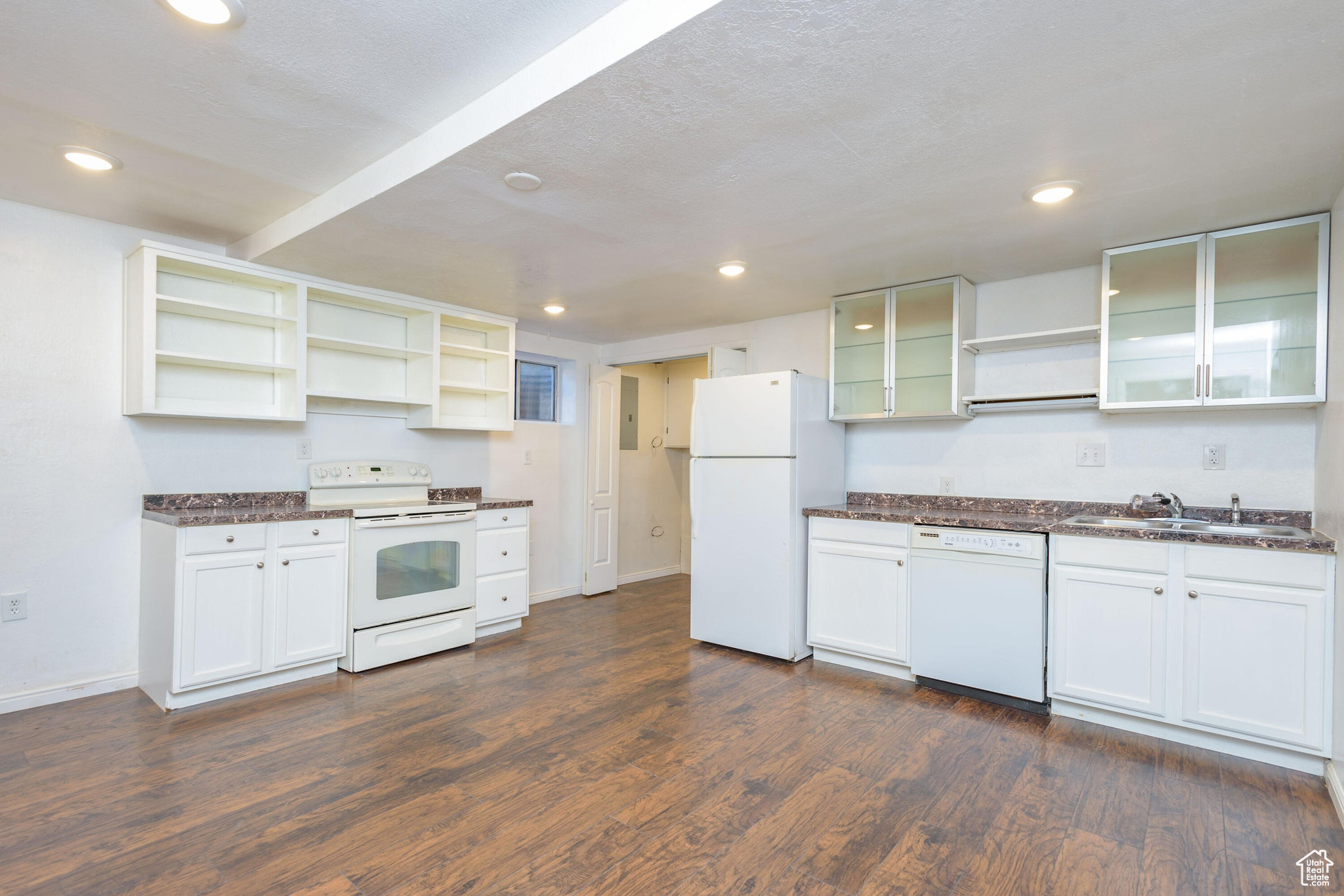 Kitchen with white cabinetry, dark hardwood / wood-style flooring, white appliances, and sink