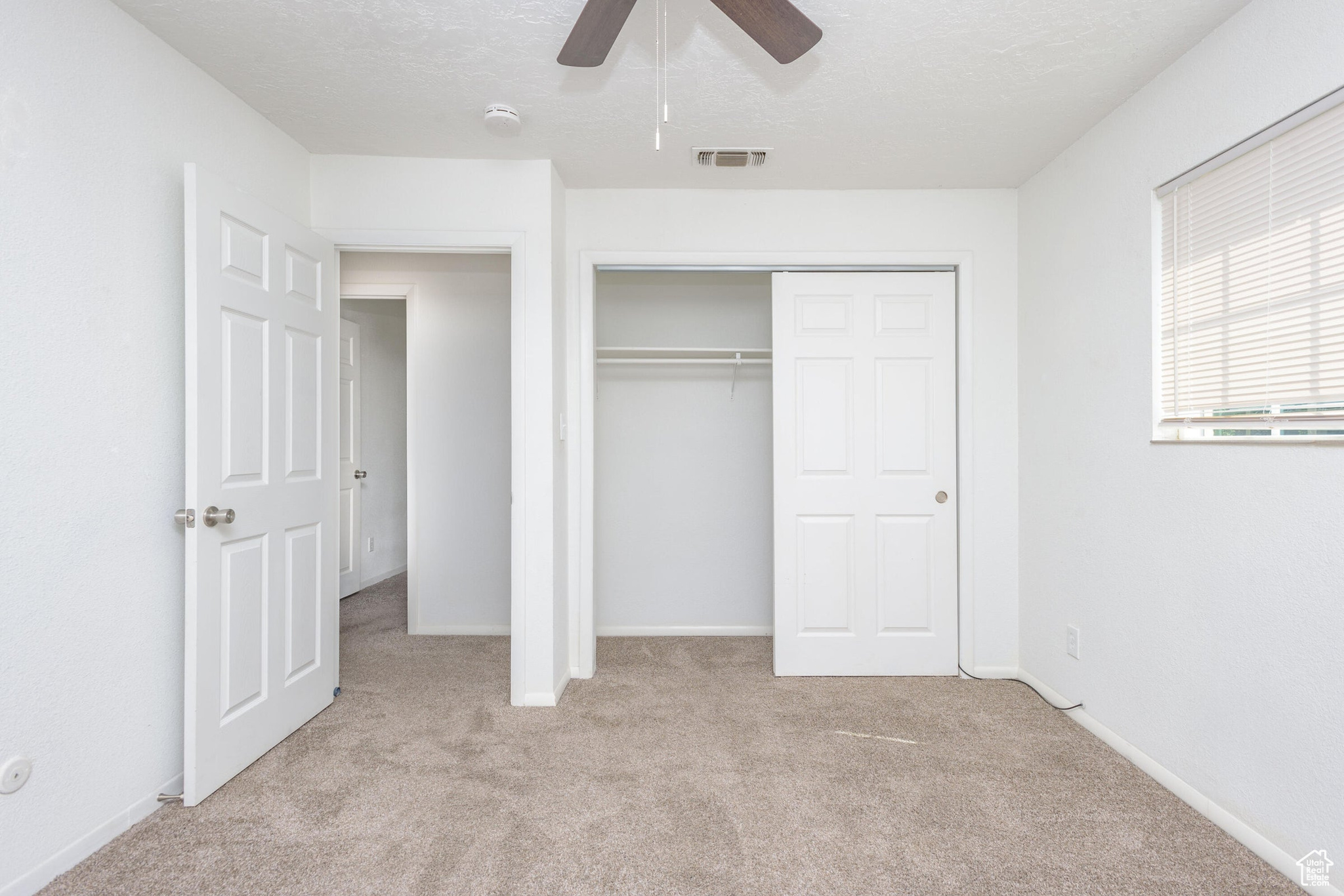 Unfurnished bedroom featuring a closet, ceiling fan, and light colored carpet