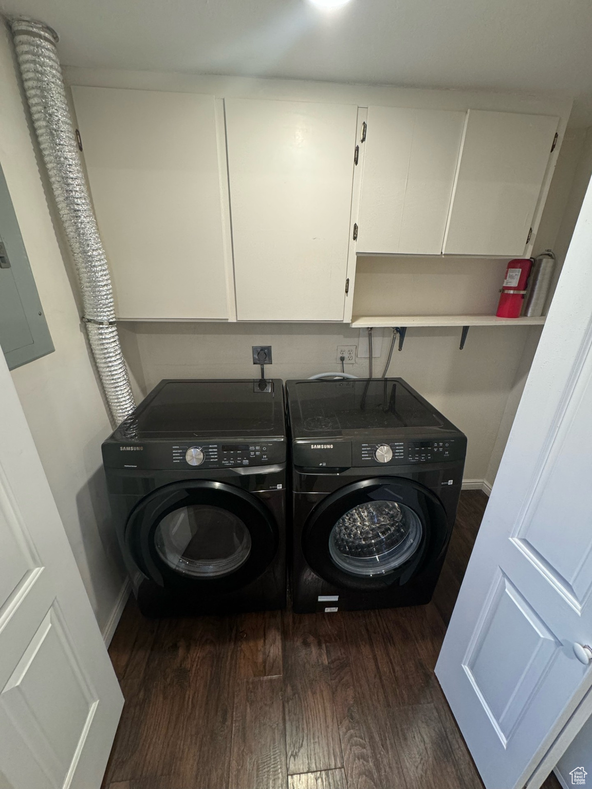 Washroom featuring separate washer and dryer, wood-type flooring, and cabinets