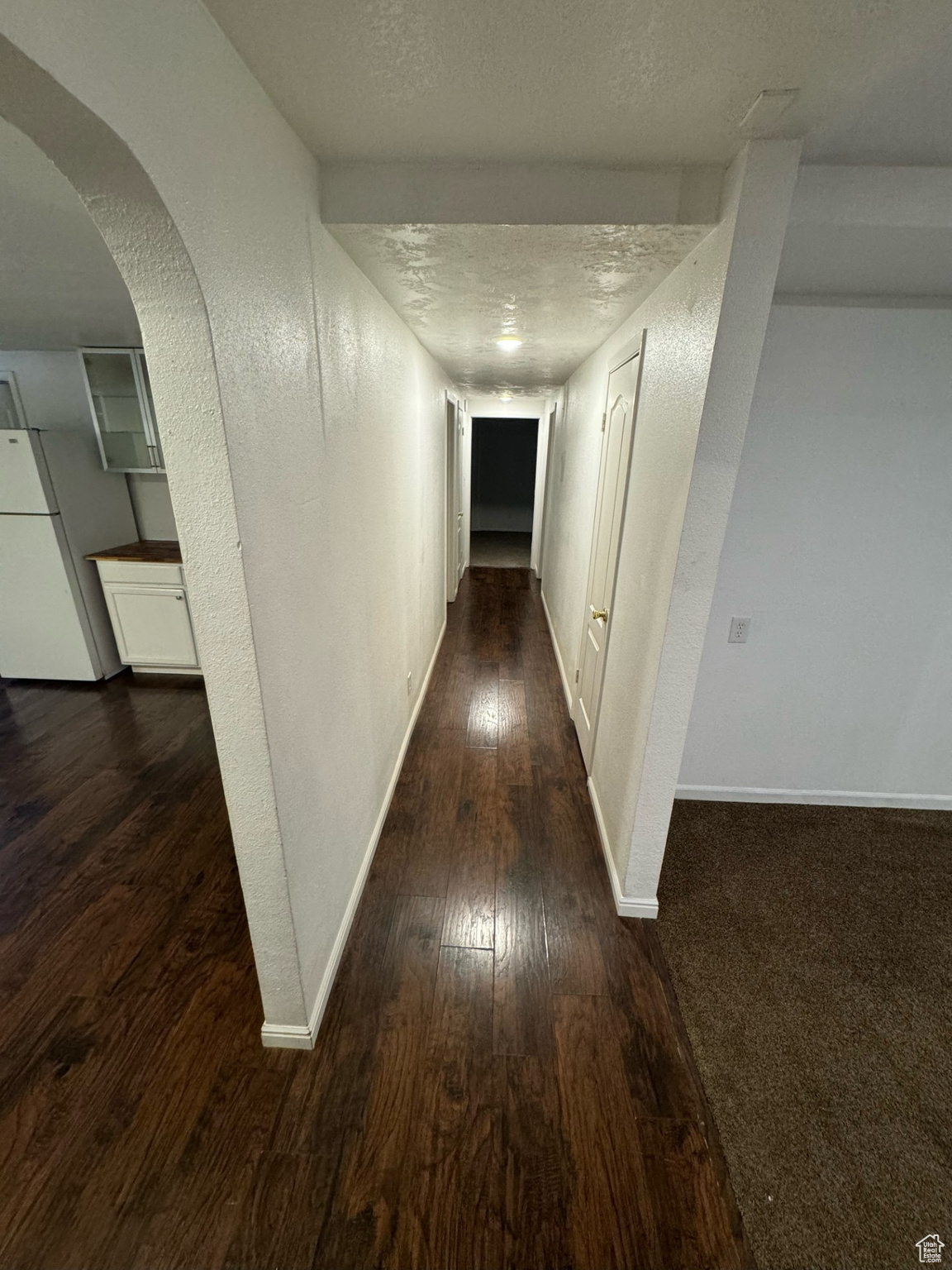 Hall with a textured ceiling and hardwood / wood-style floors