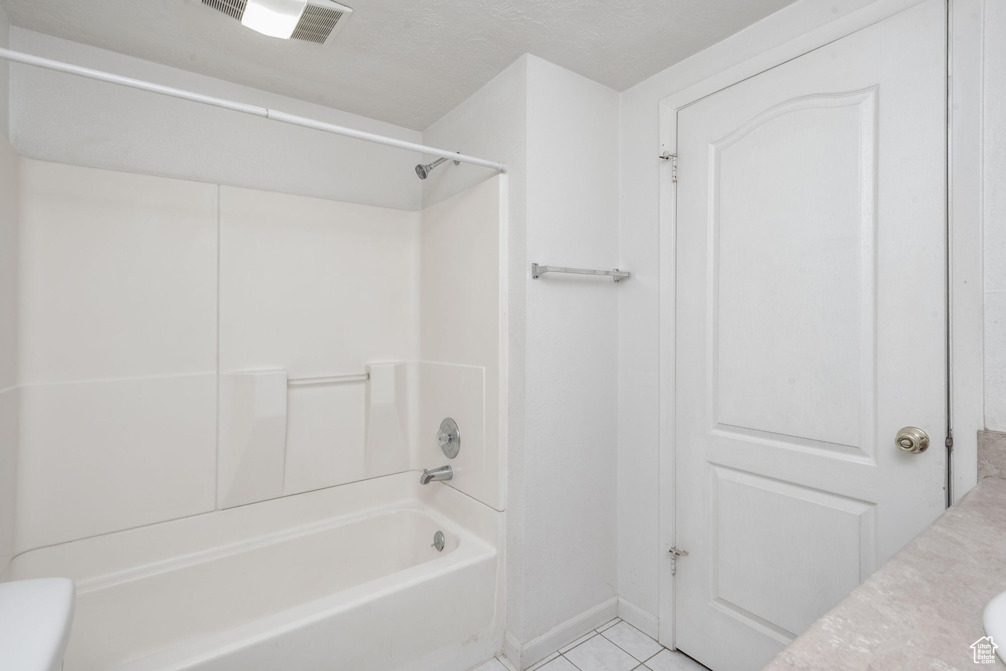 Bathroom with bathing tub / shower combination, toilet, and tile patterned floors