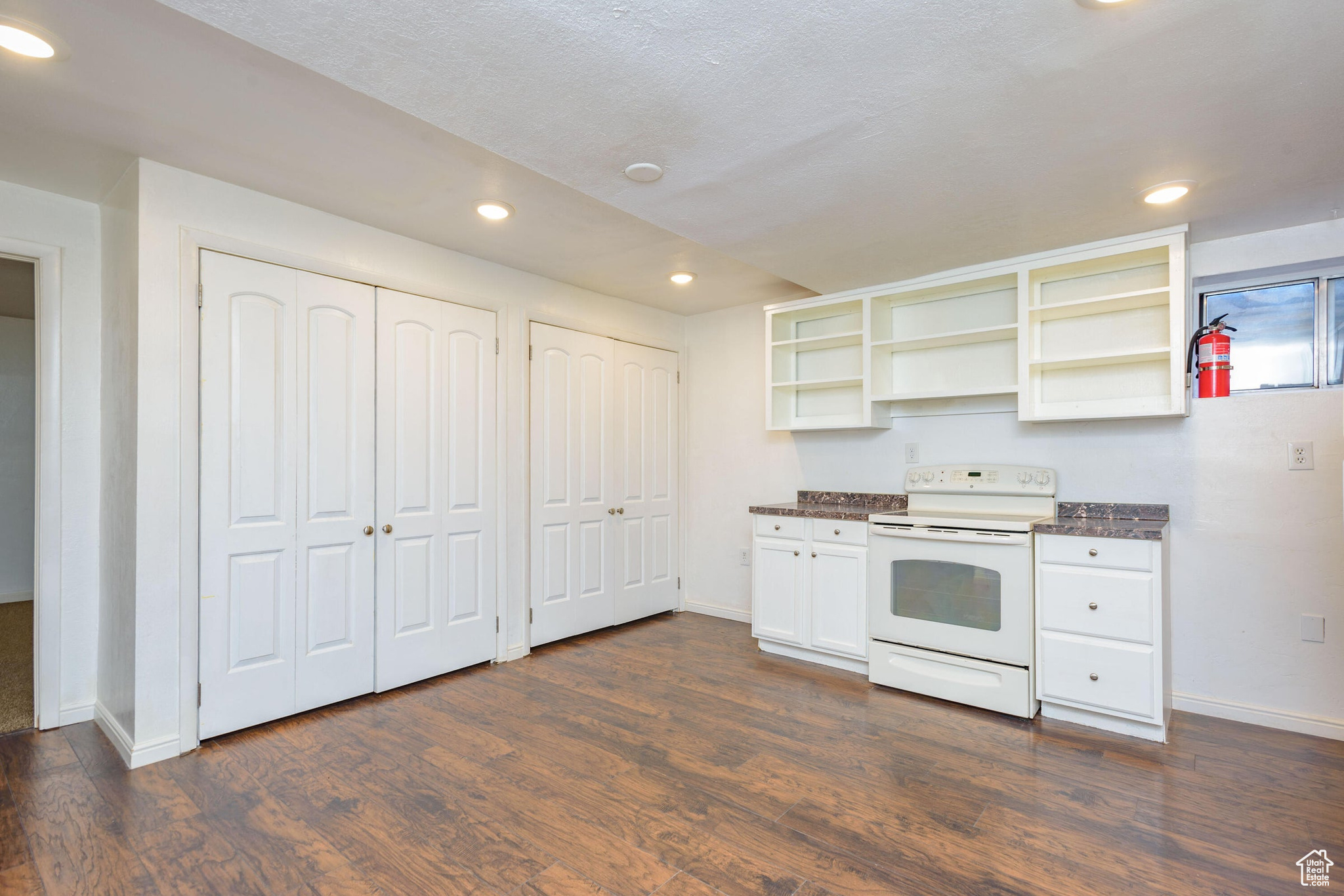 Kitchen featuring white cabinetry, dark hardwood / wood-style floors, and white range with electric stovetop