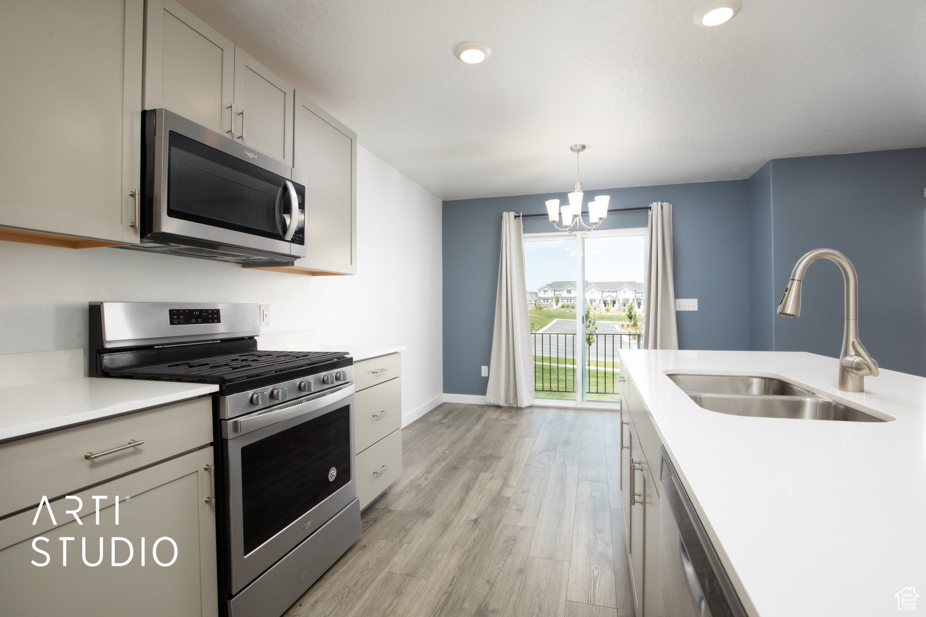 Kitchen featuring stove, sink, dishwashing machine, light wood-type flooring, and a chandelier