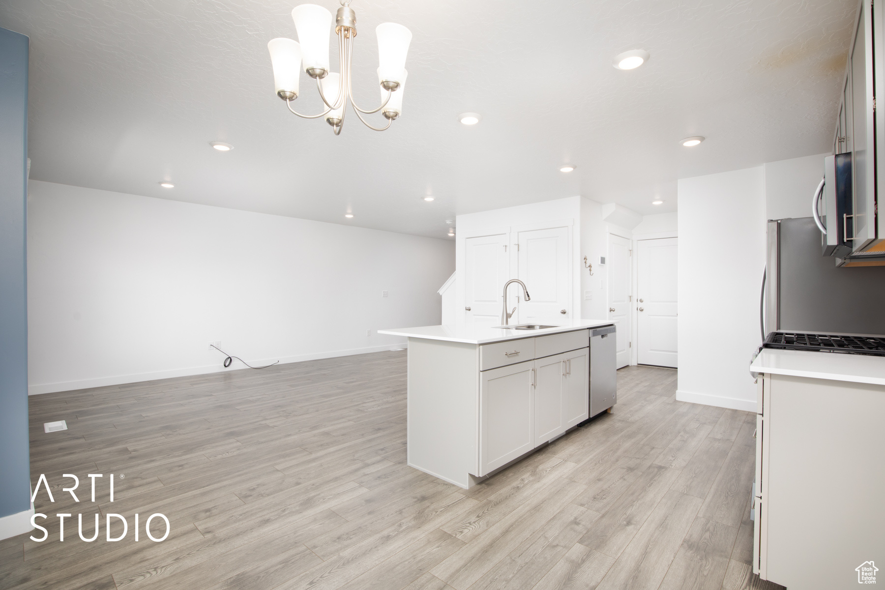 Kitchen with a center island with sink, decorative light fixtures, sink, and light wood-type flooring