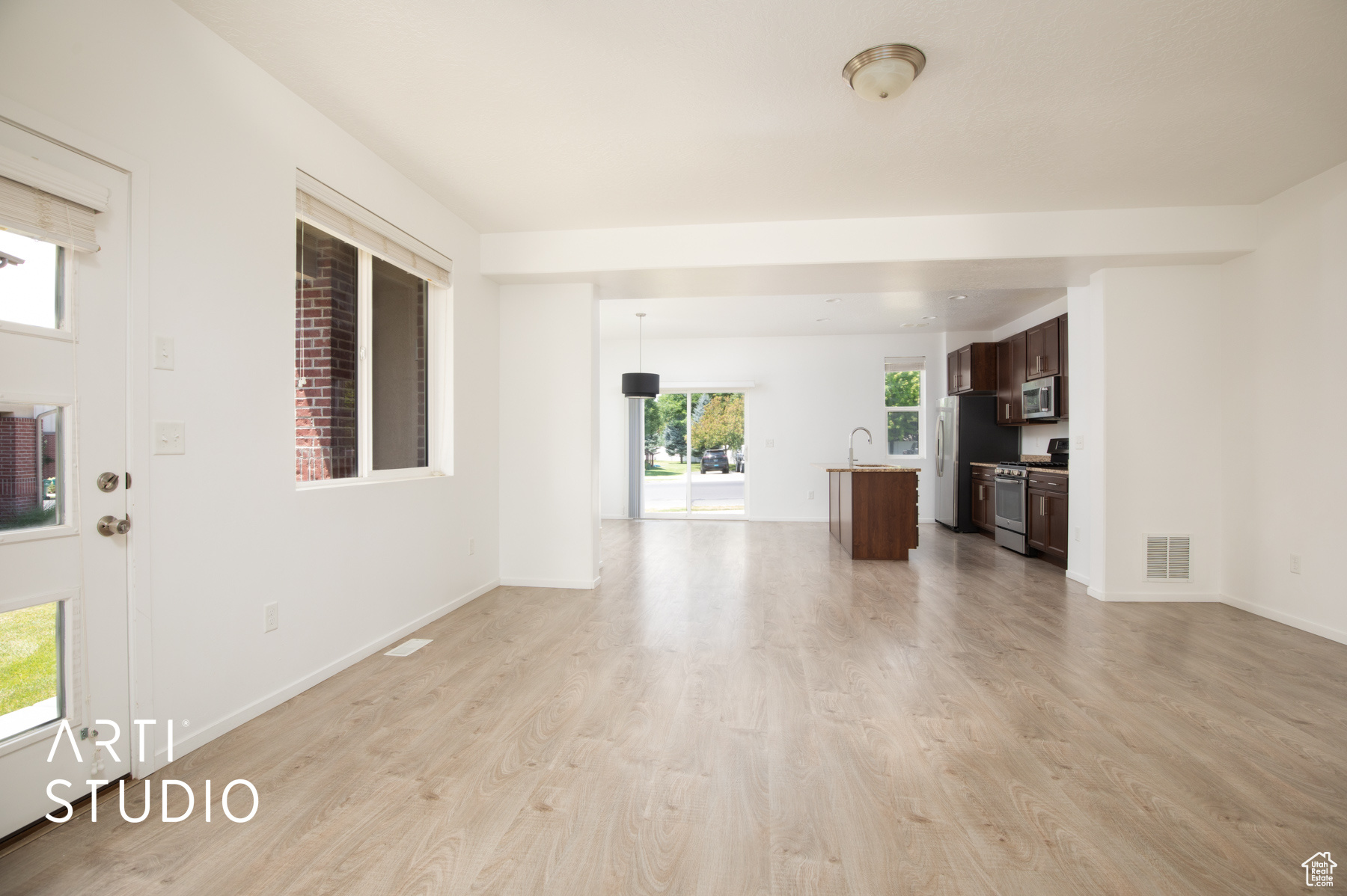 Unfurnished living room featuring sink, light hardwood / wood-style flooring, and a healthy amount of sunlight