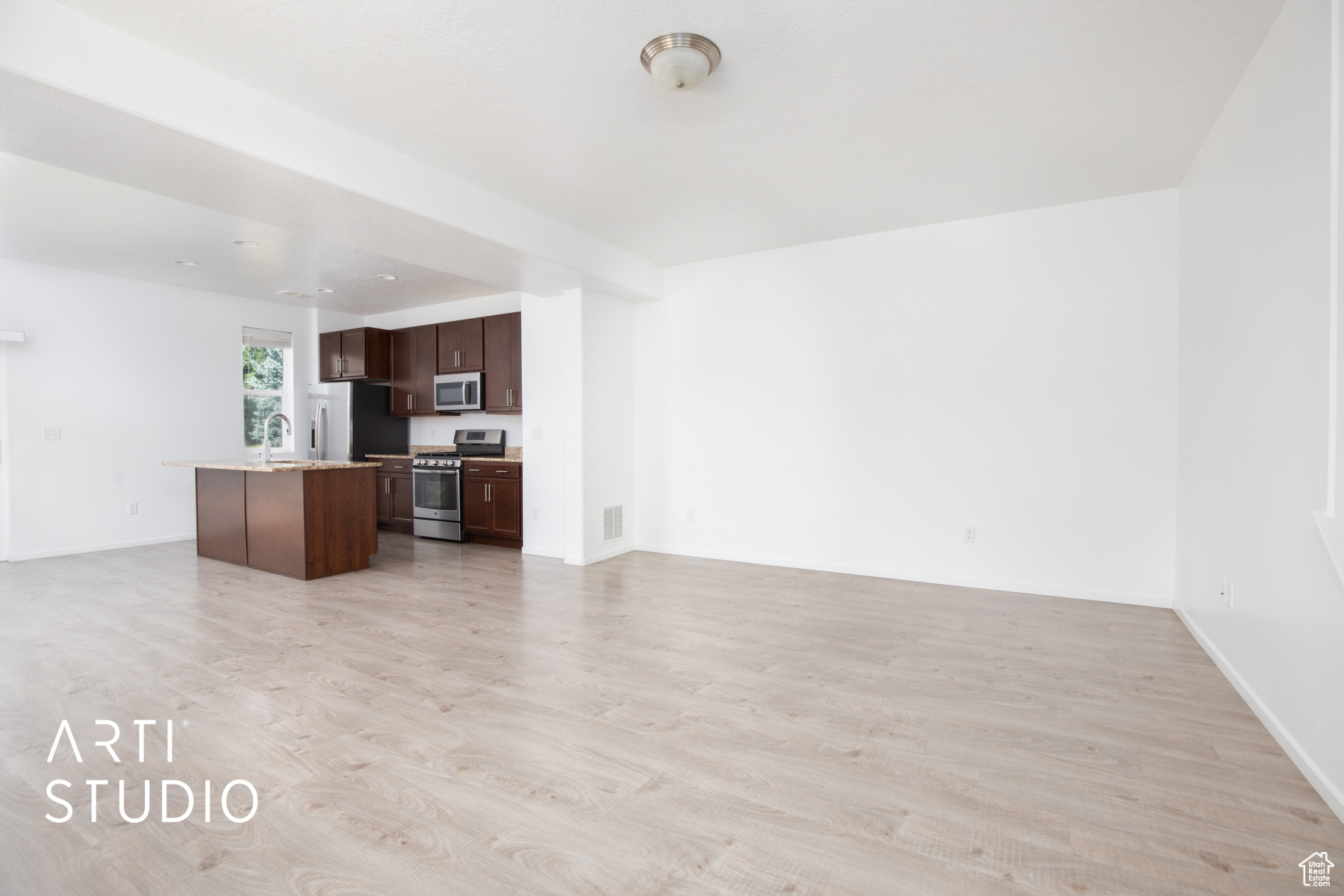 Unfurnished living room with sink and light hardwood / wood-style flooring