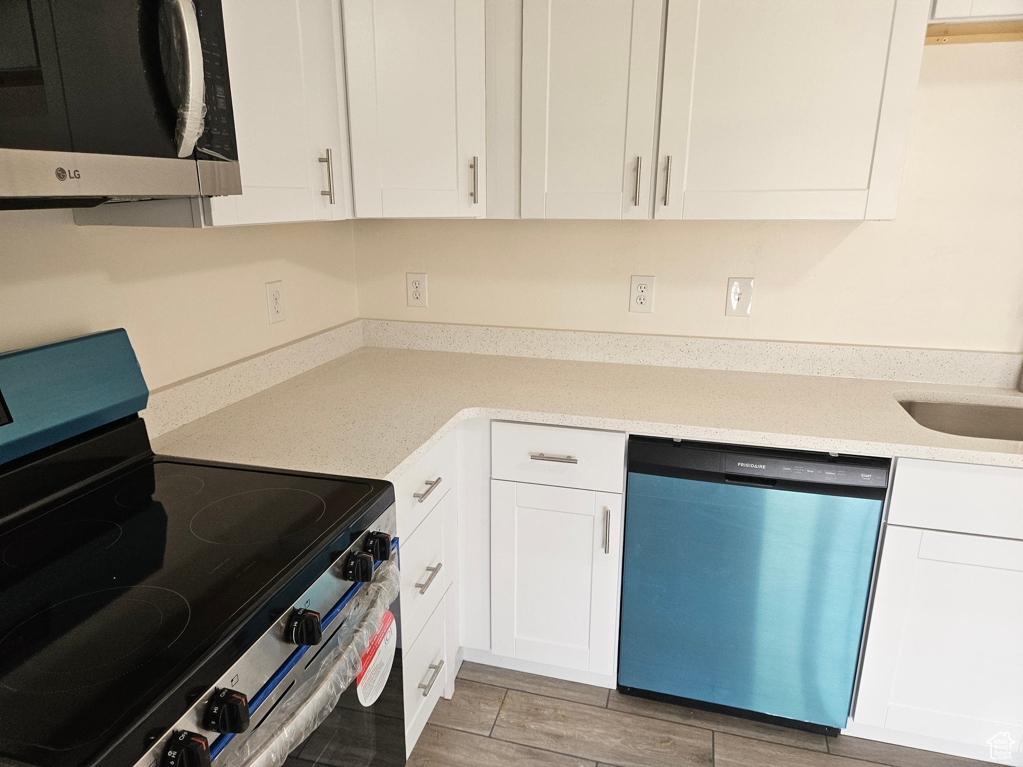 Kitchen with appliances with stainless steel finishes, white cabinets, and light stone countertops