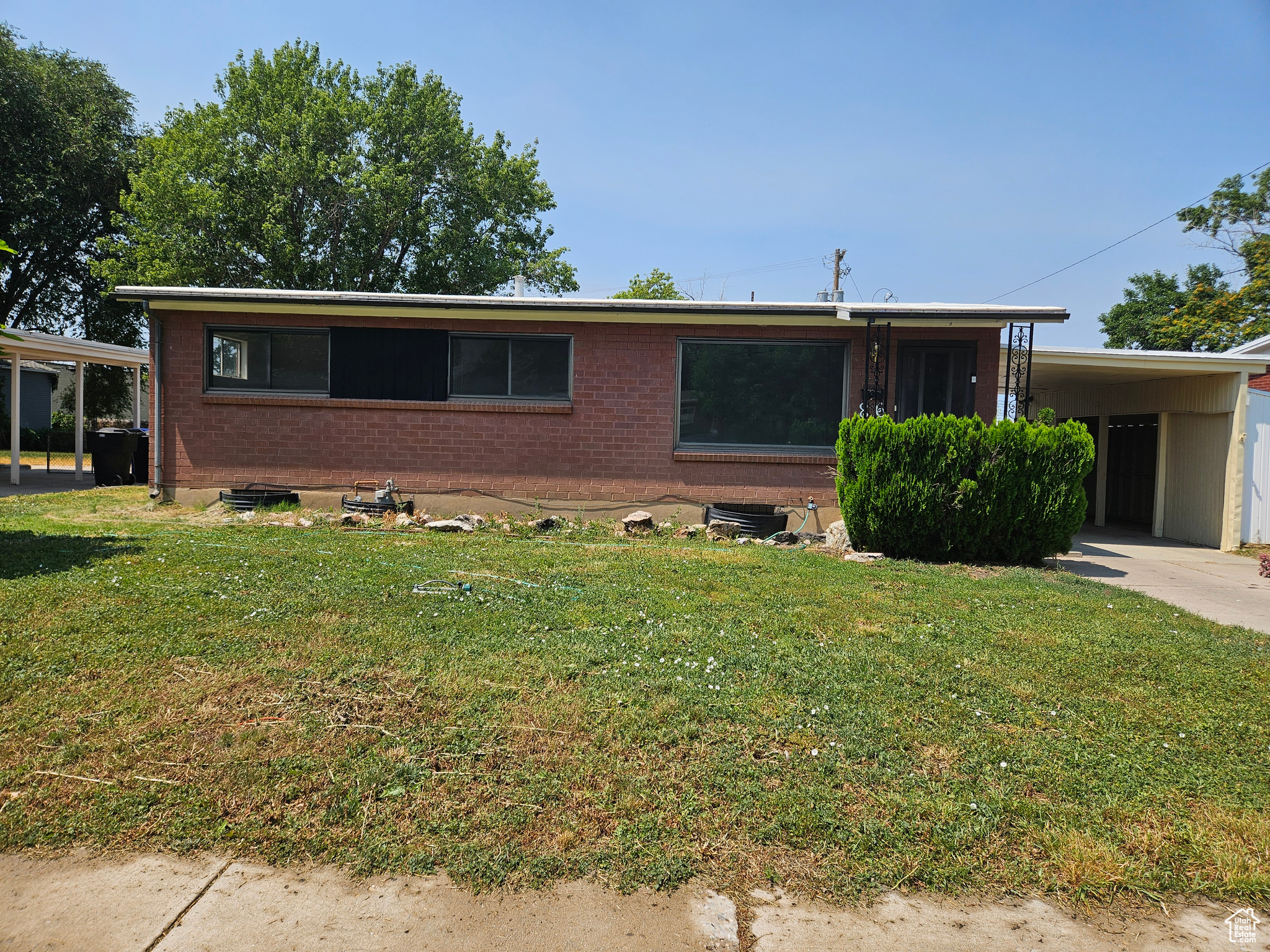 View of front facade featuring a carport and a front yard