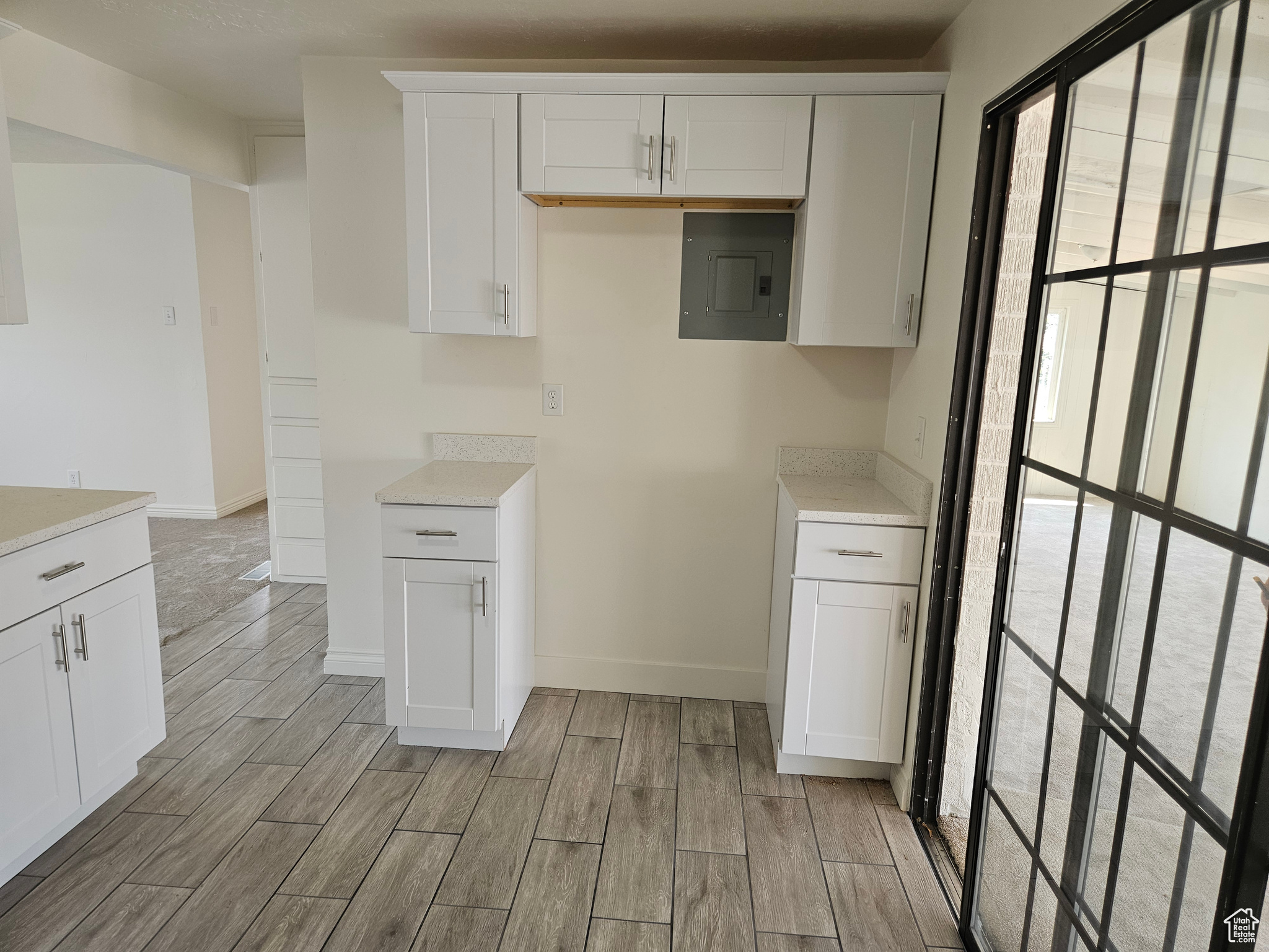 Kitchen with white cabinetry, light hardwood / wood-style floors, and electric panel