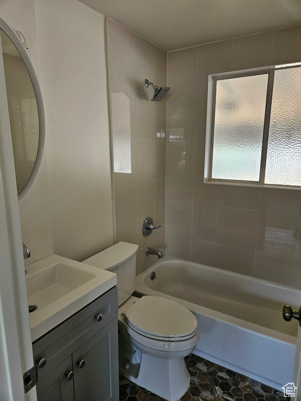 Full bathroom with toilet, tile patterned floors, tiled shower / bath combo, and vanity