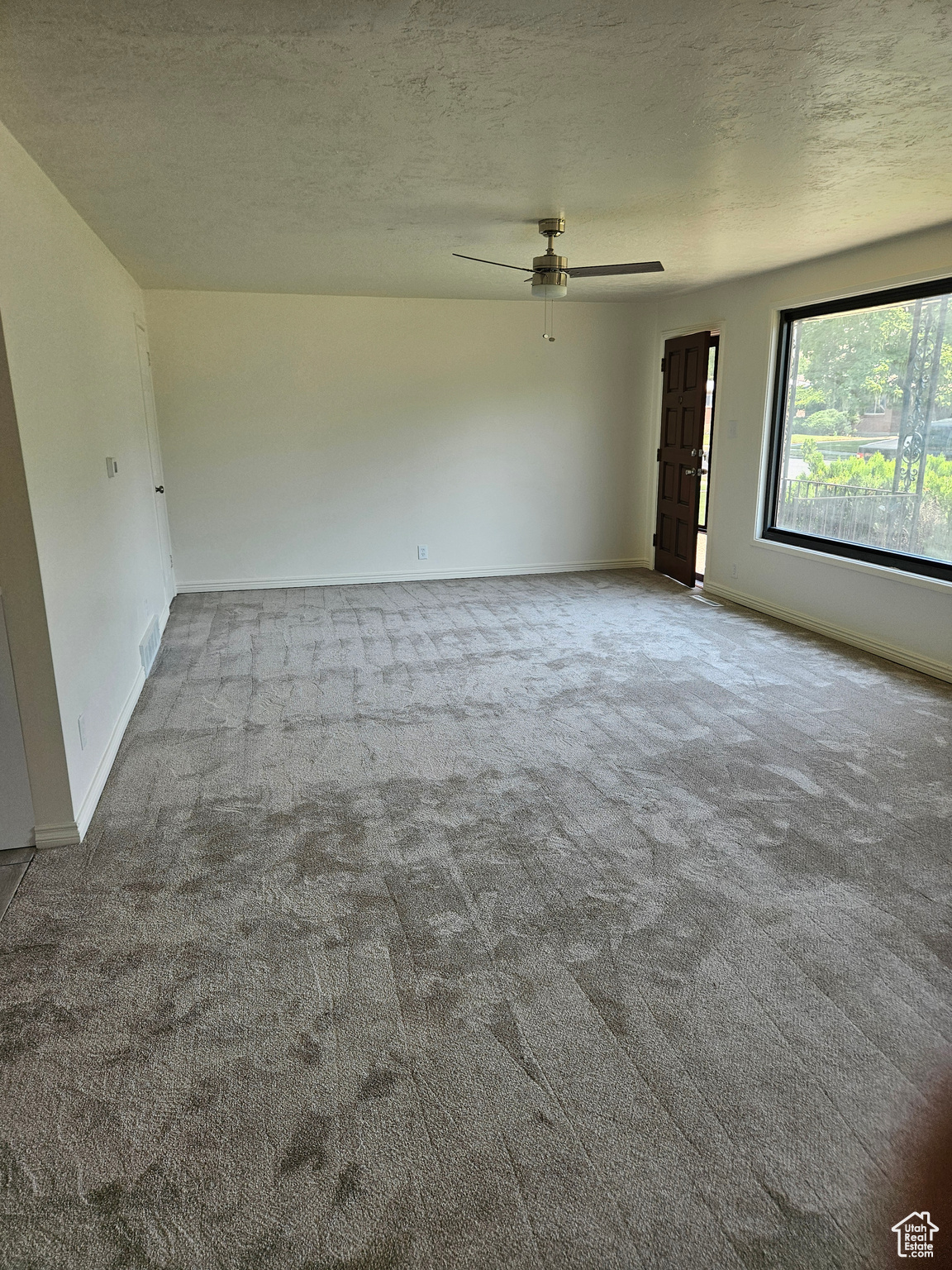 Carpeted empty room featuring a textured ceiling and ceiling fan