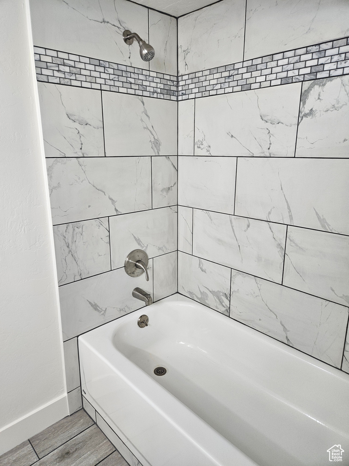 Bathroom with tiled shower / bath combo and hardwood / wood-style flooring