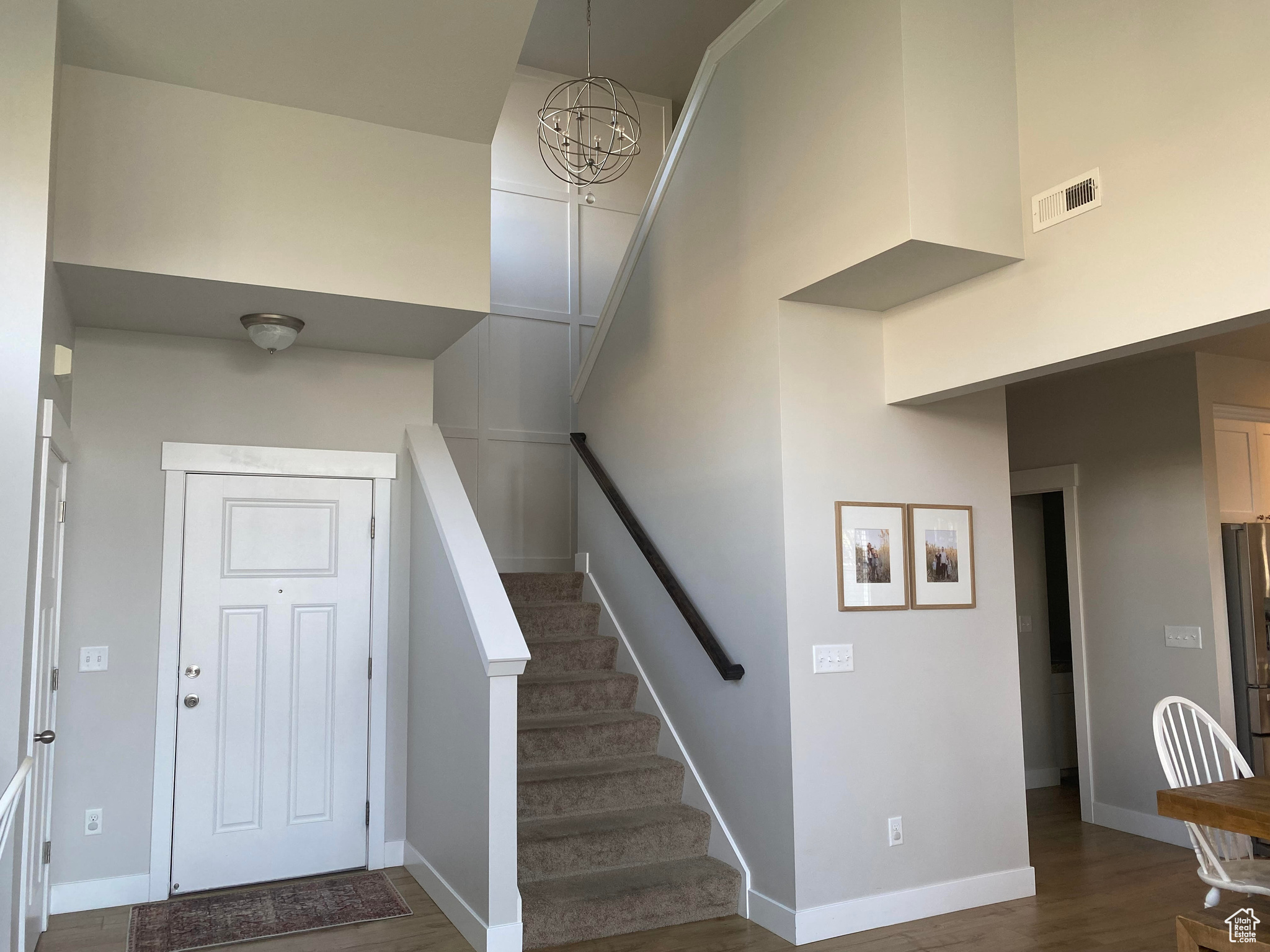 Interior space featuring dark wood-type flooring, a towering ceiling, and a chandelier