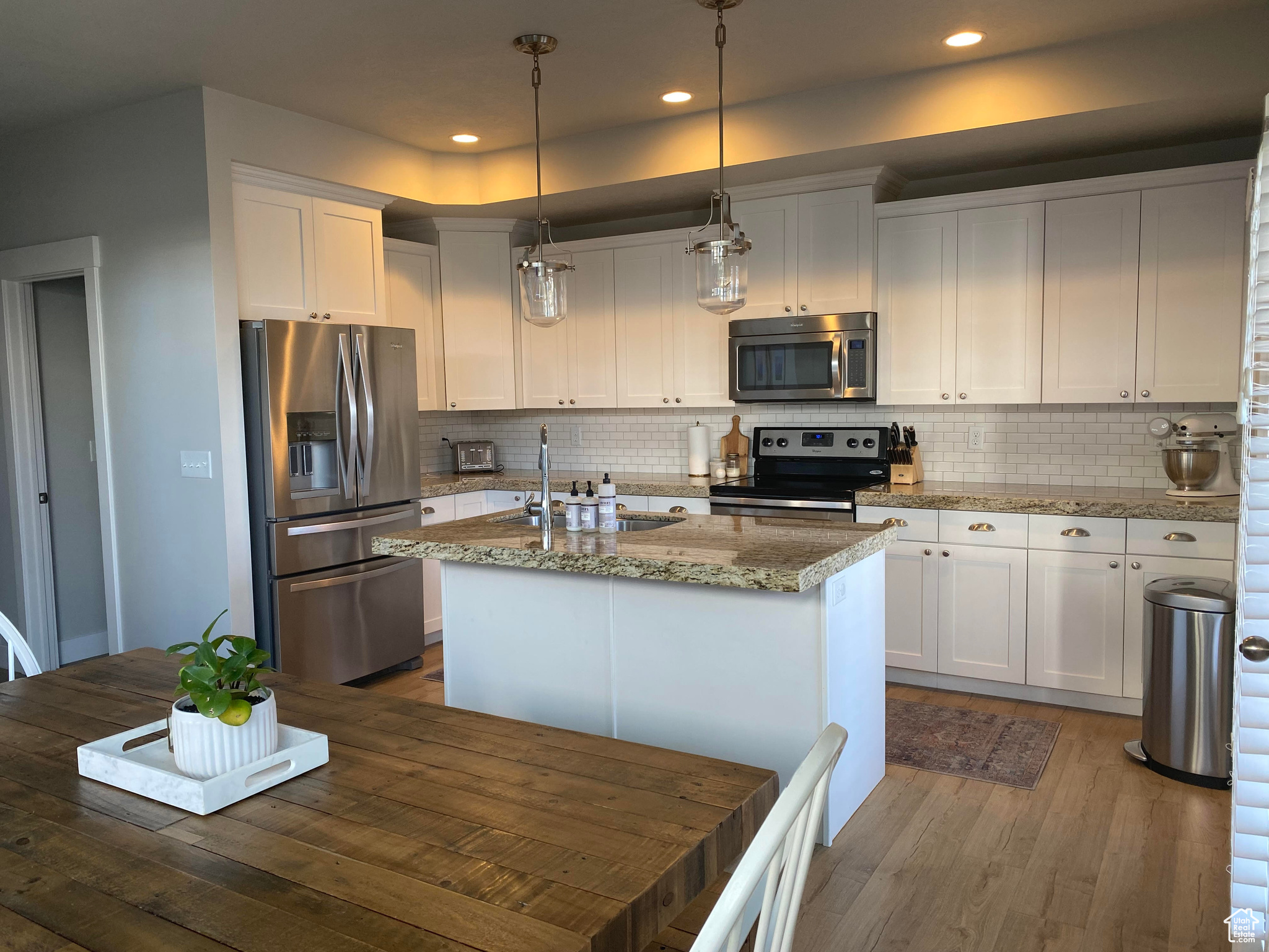 Kitchen with white cabinetry, tasteful backsplash, sink, appliances with stainless steel finishes, and a kitchen island with sink