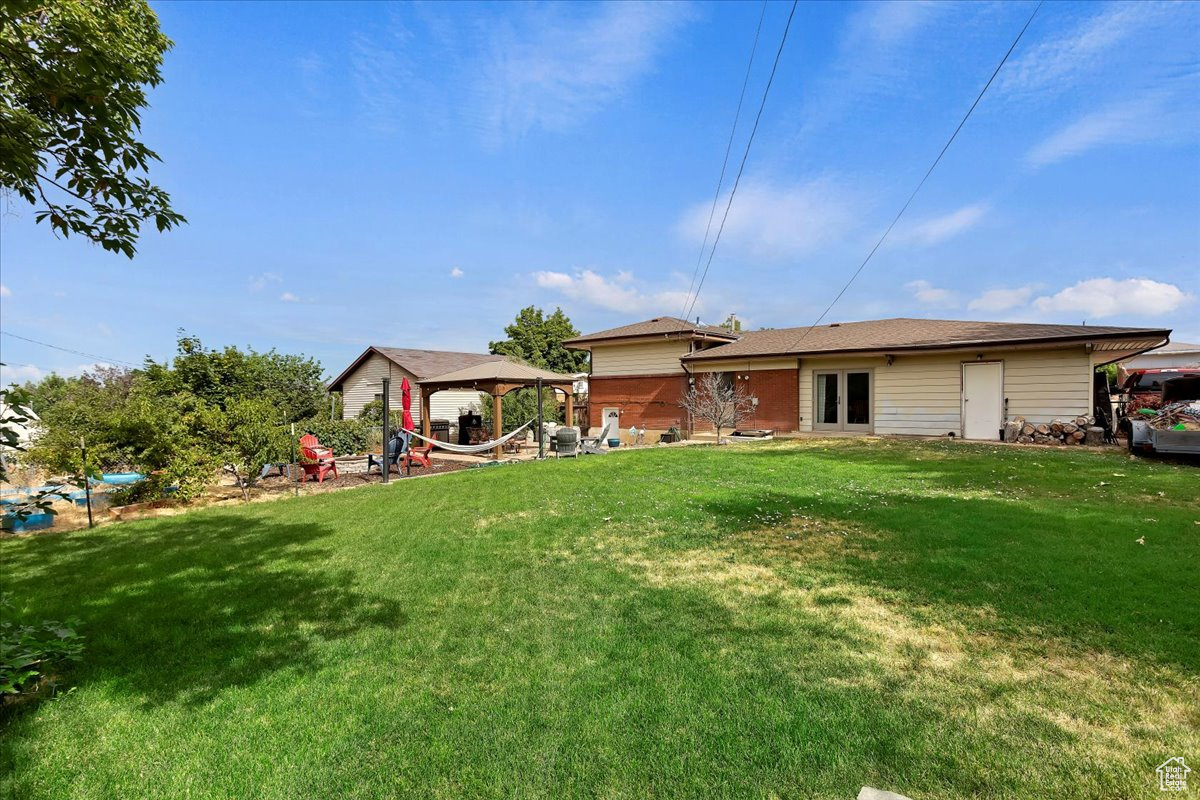 Rear view of property with a gazebo and a yard