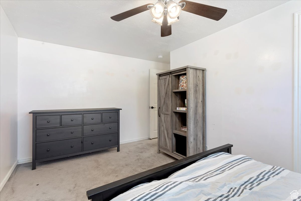 Carpeted bedroom featuring ceiling fan