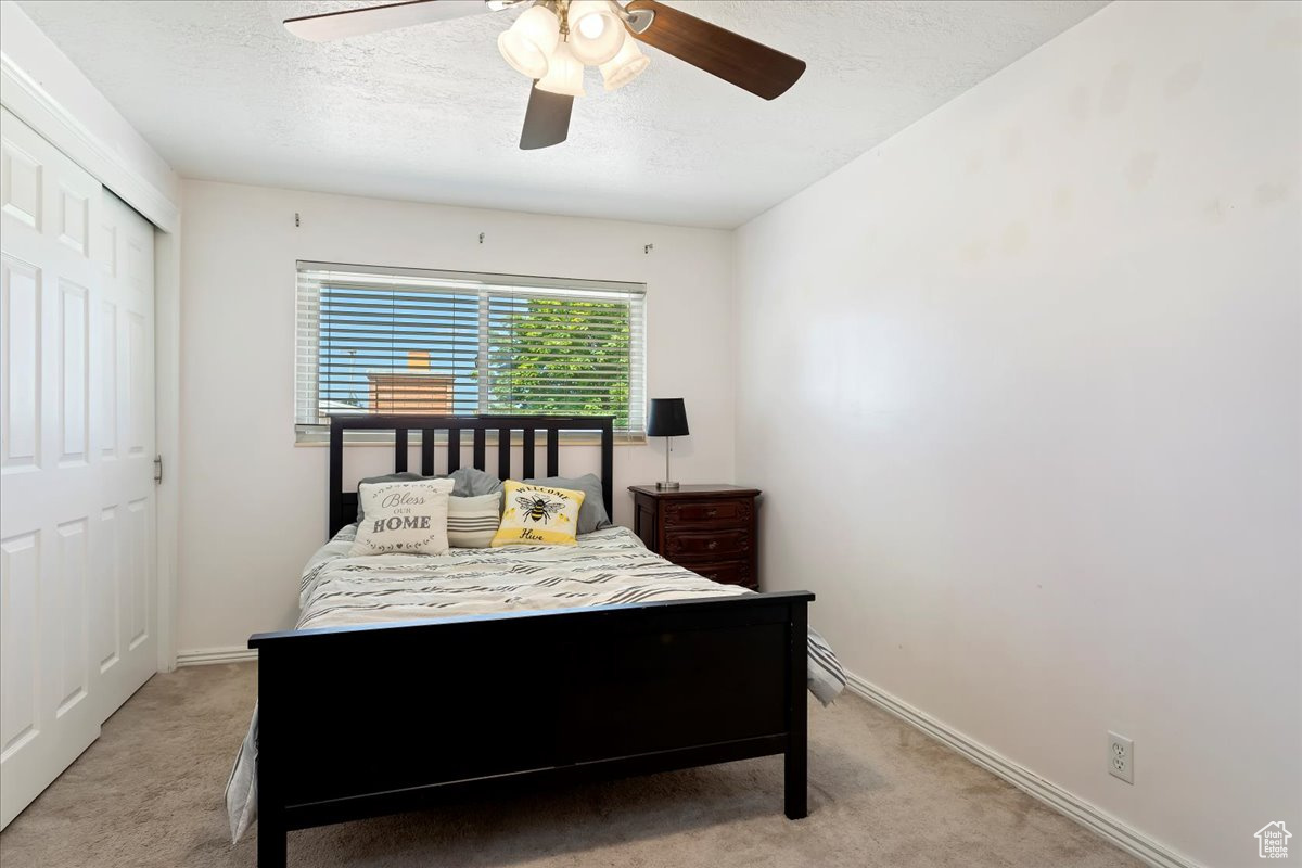 Carpeted bedroom with a closet and ceiling fan