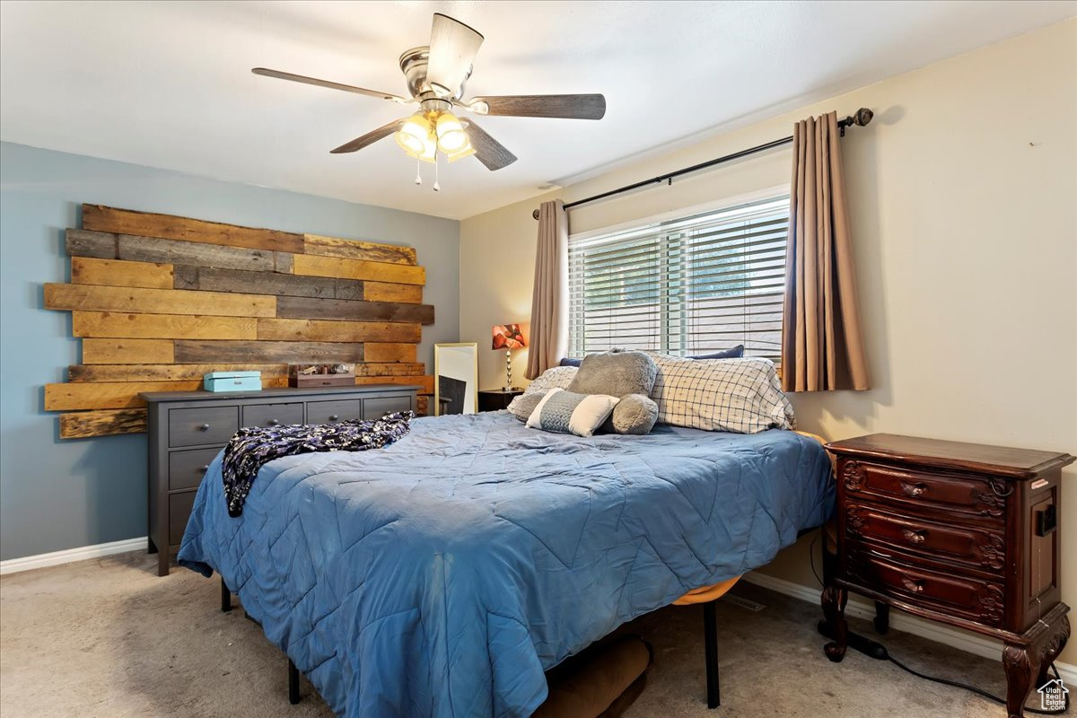 Carpeted bedroom featuring ceiling fan