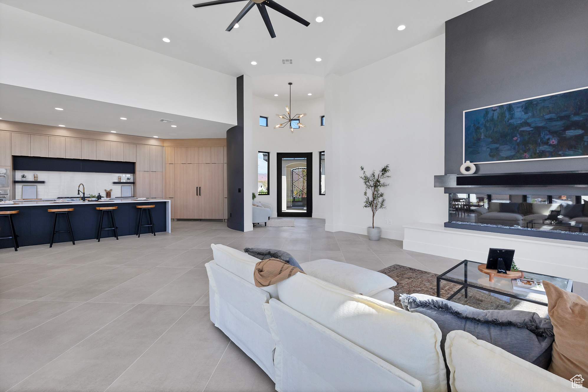 Tiled living room with a high ceiling, sink, and ceiling fan with notable chandelier