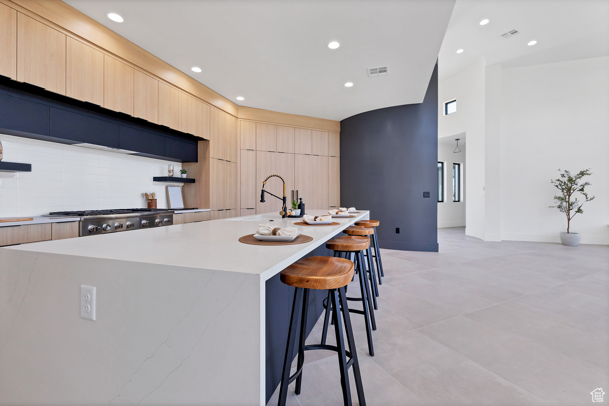 Kitchen with a breakfast bar, sink, light tile patterned floors, and an island with sink