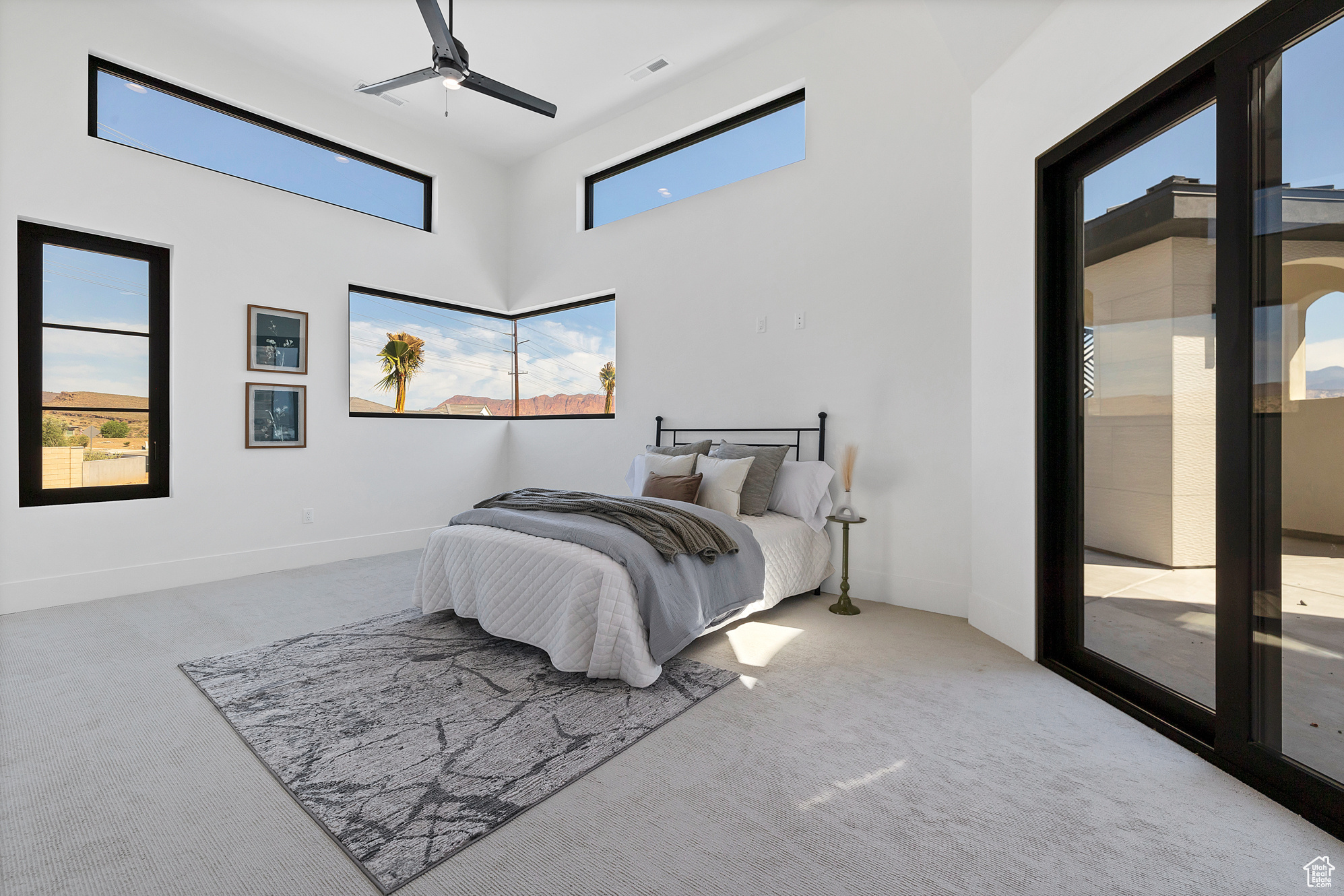 Bedroom with carpet floors, ceiling fan, access to exterior, and a towering ceiling