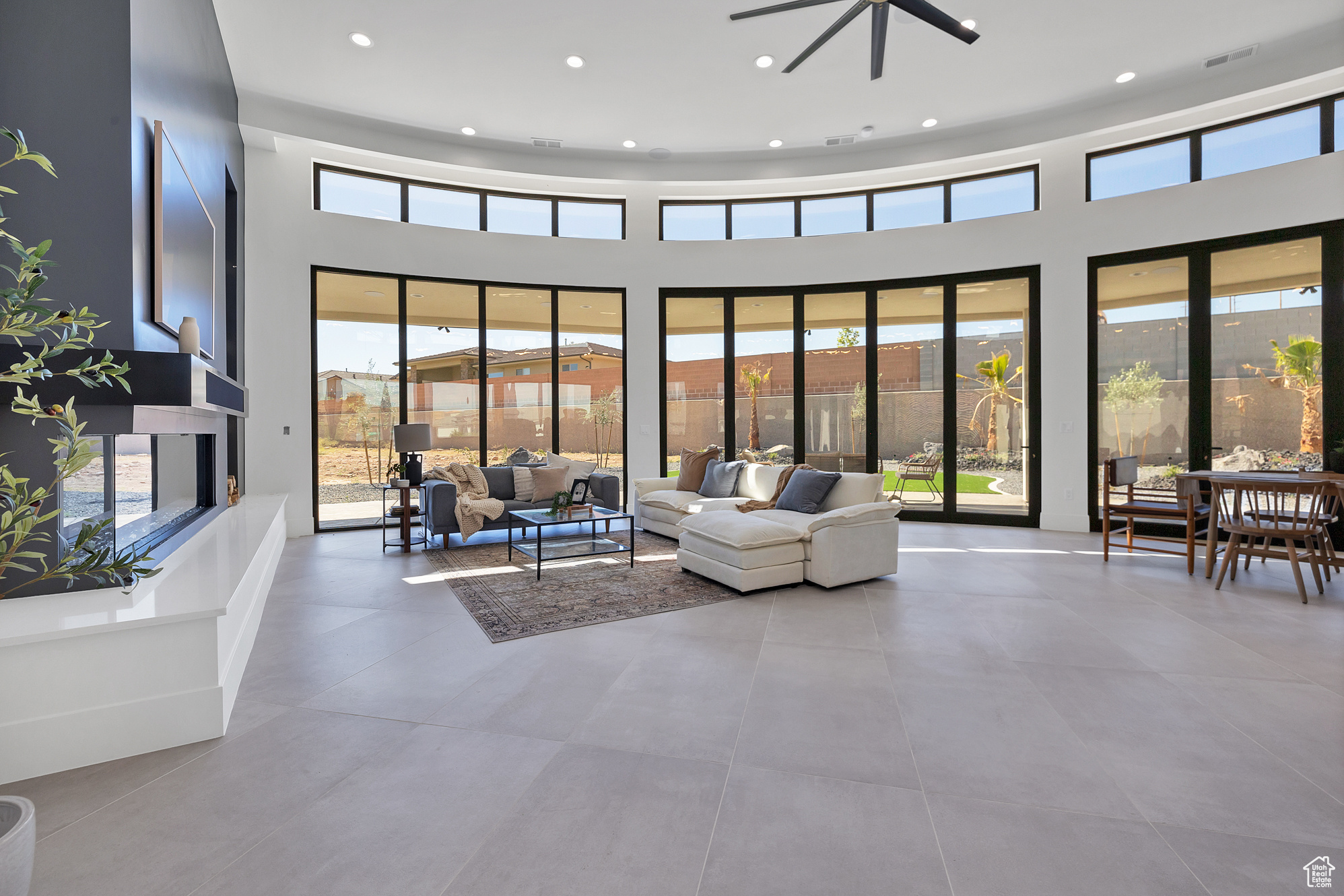 Tiled living room featuring a wealth of natural light, ceiling fan, and a high ceiling